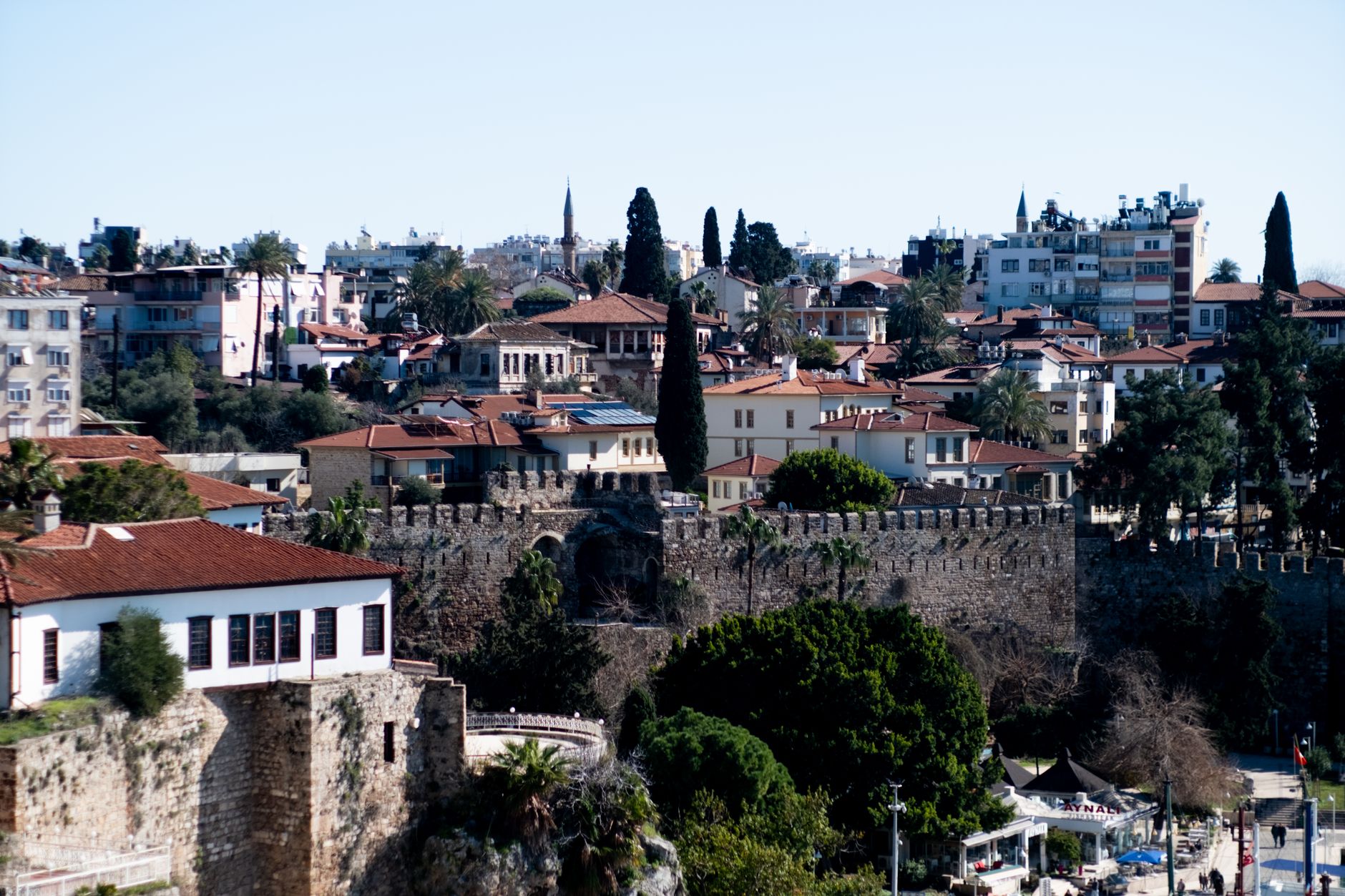 A view of Kaleiçi in Antalya showcasing traditional architecture, stone walls, and greenery.
