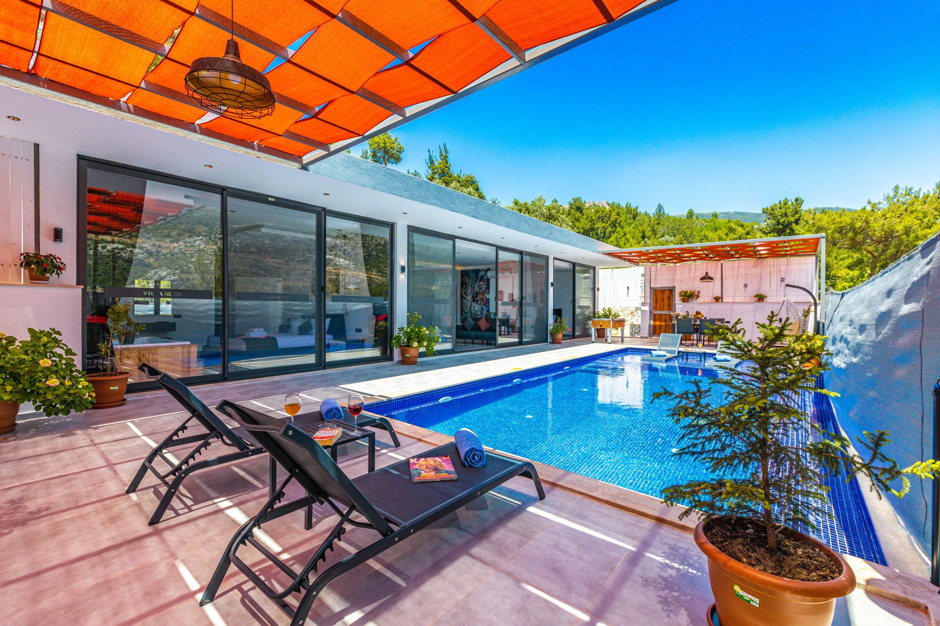 Modern villa with a swimming pool, sun loungers, and lush greenery.