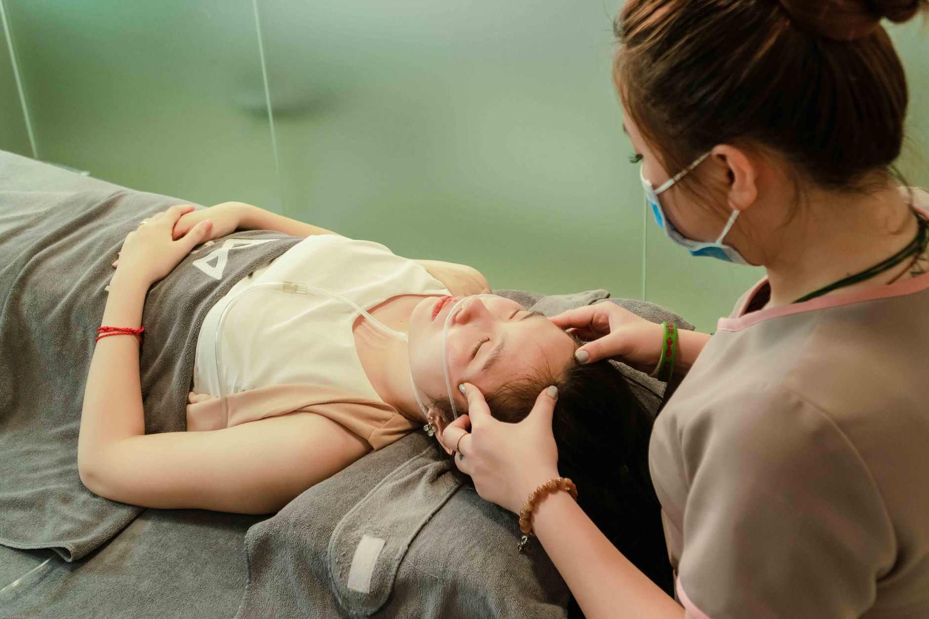A woman receiving a facial treatment with an oxygen mask in a spa setting.