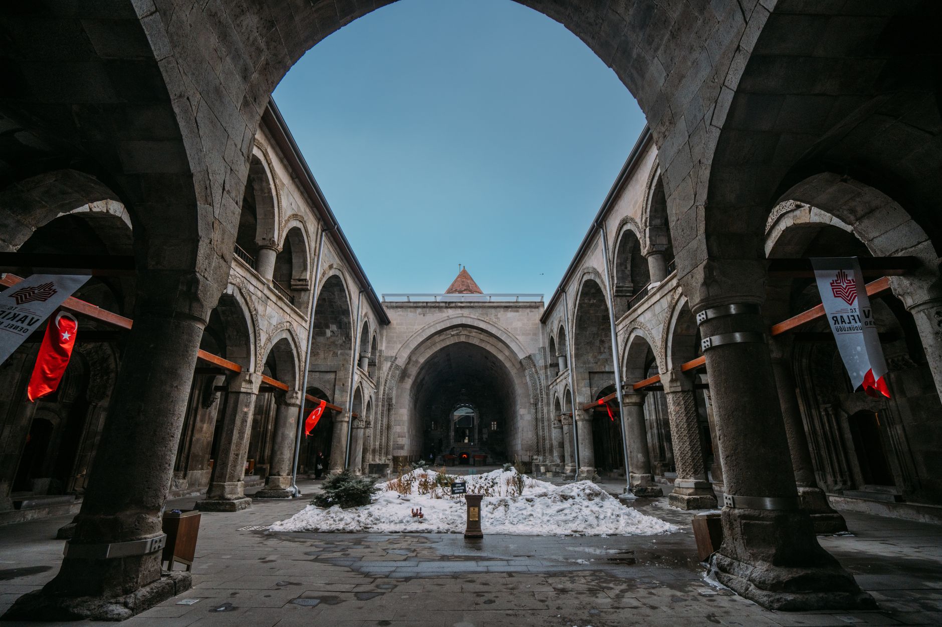 View of historic arches in Kayseri, with snow on the ground and Turkish flags, showcasing the city's rich heritage.