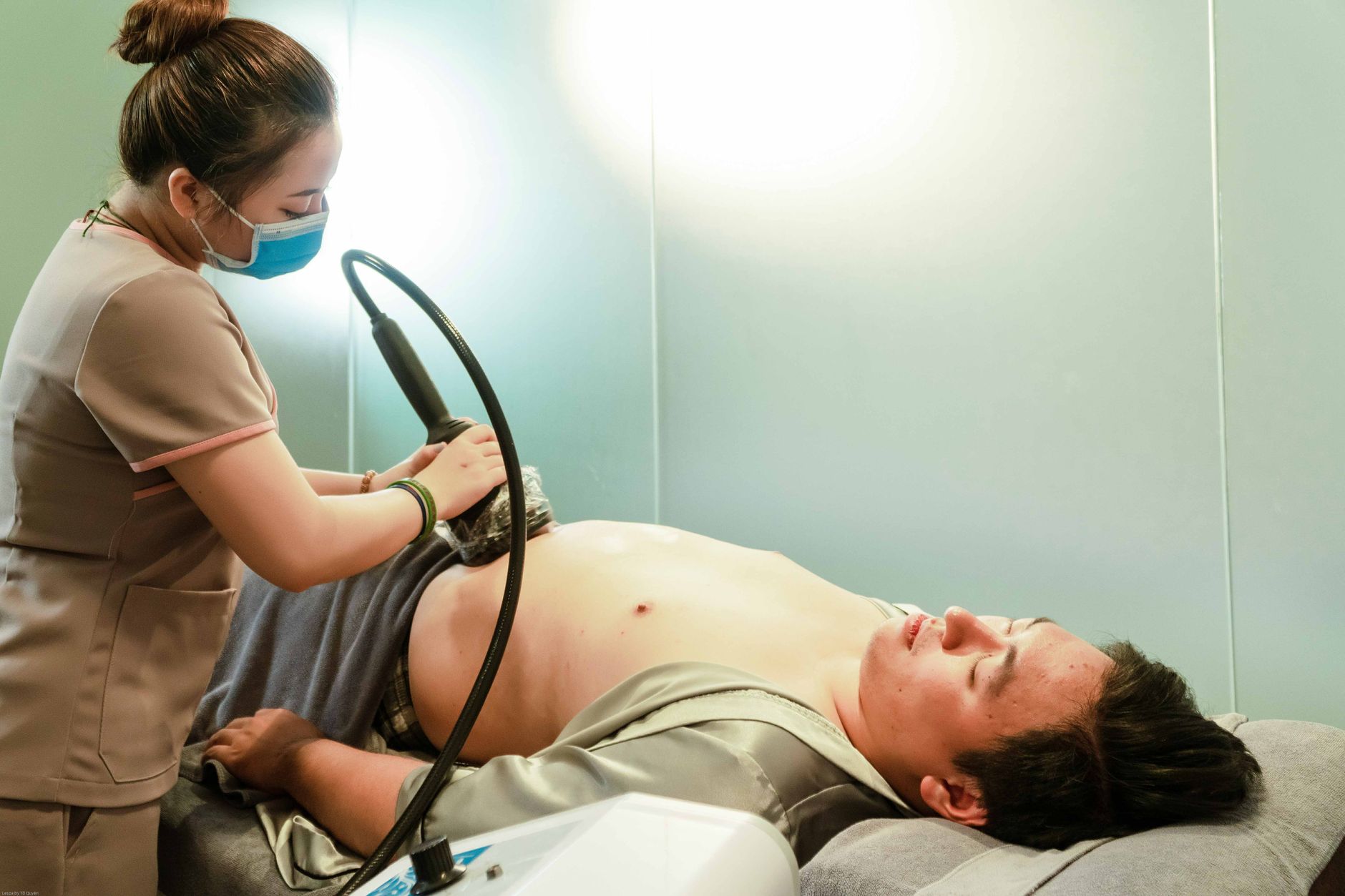 A patient undergoing fat-freezing treatment on the abdomen in a clinic.