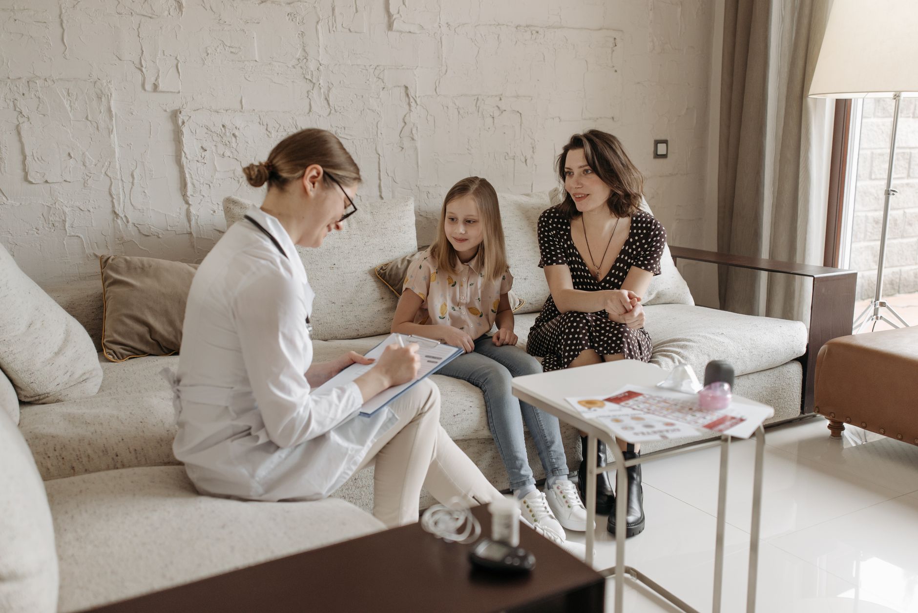 A mother and daughter receive counseling from a healthcare professional about cochlear implant rehabilitation.