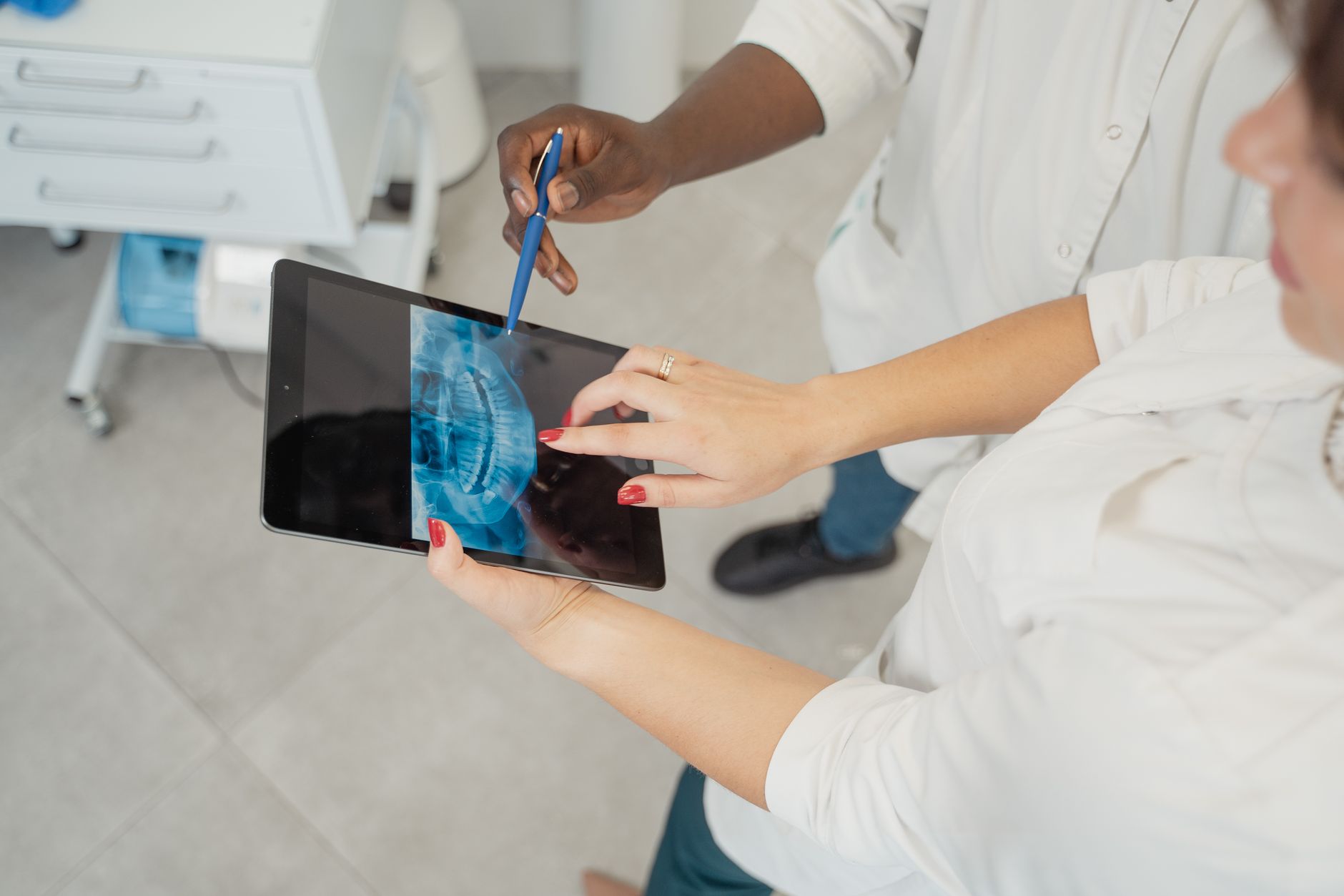 Clinician analyzing an x-ray on a tablet with a patient in a medical setting.