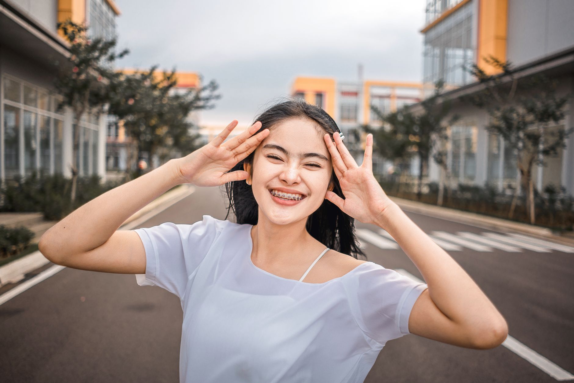 A happy teenager with clear aligners poses in a modern outdoor setting in Türkiye, promoting child-friendly orthodontics.