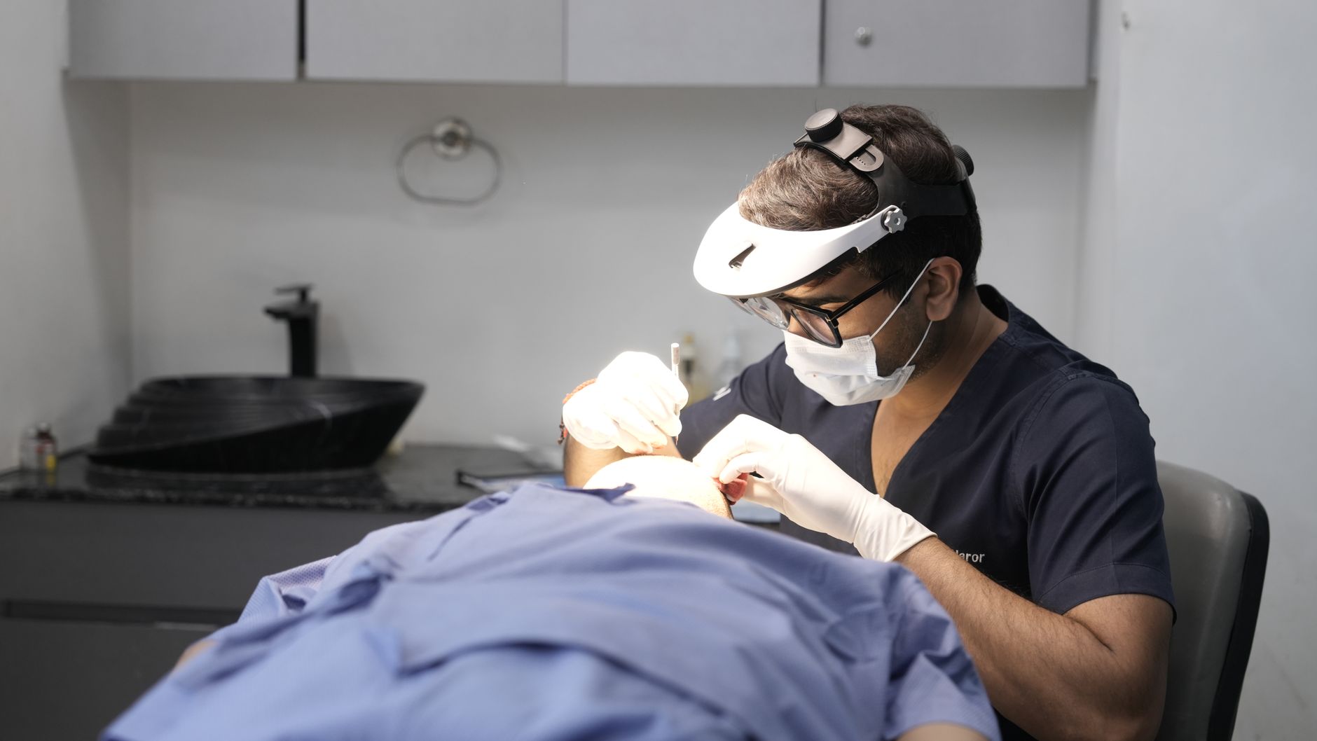A dermatologist uses a dermatoscope on a patient's skin in a modern clinic.