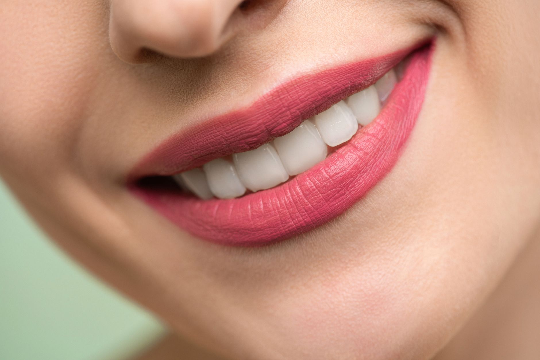 Close-up of a smiling woman showcasing a natural makeover, highlighting her pink lips and white teeth.