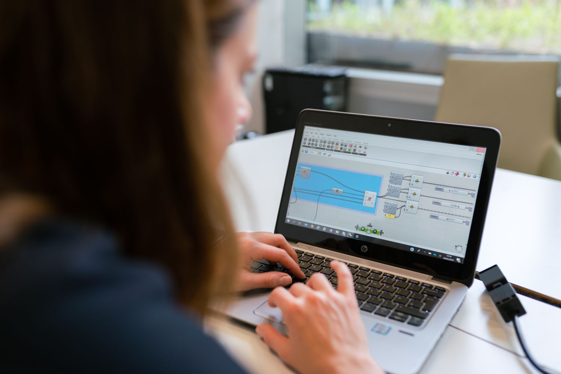 A person working on a laptop displaying a 3D digital smile simulation with teeth design.