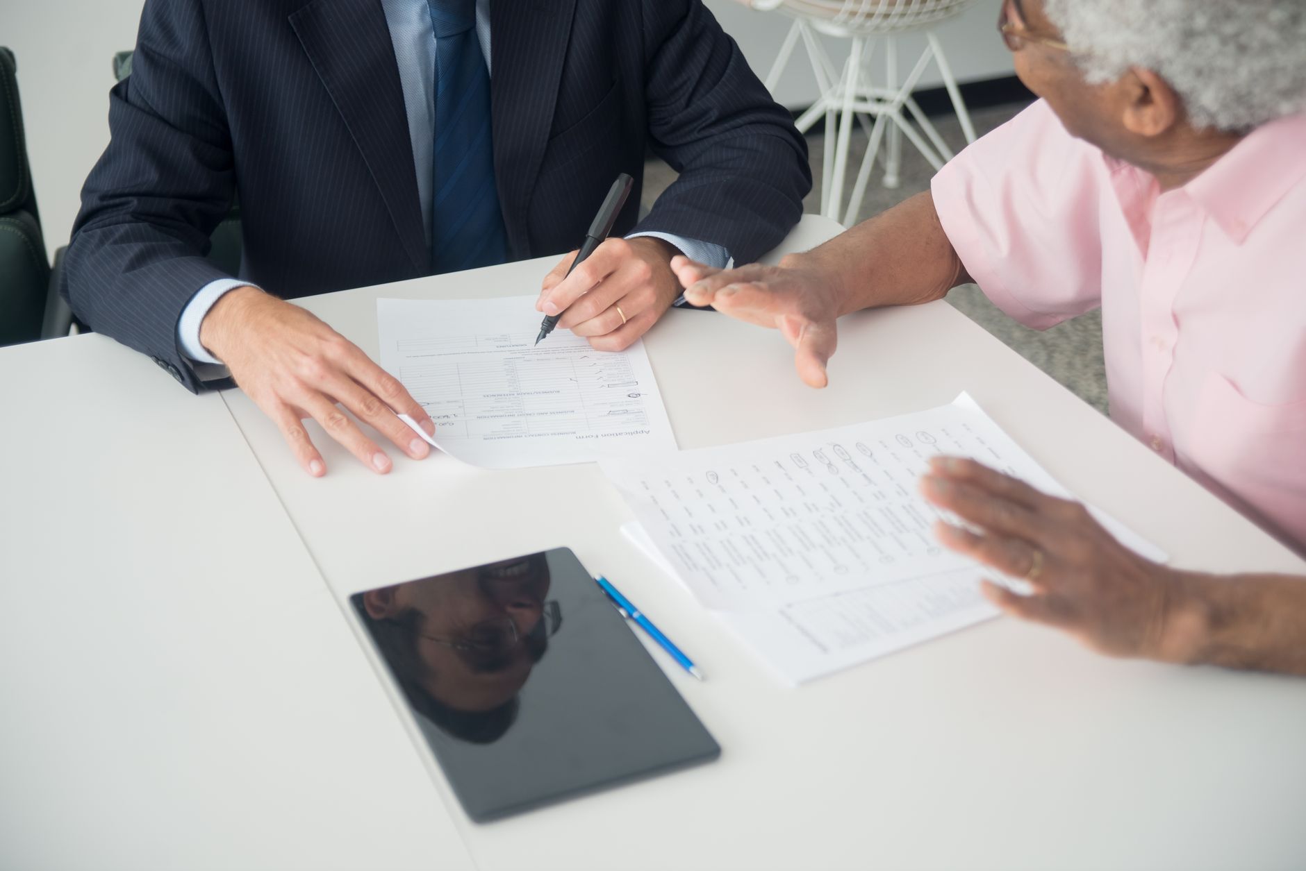 A hospital staff member discussing insurance options with an international patient at a table.