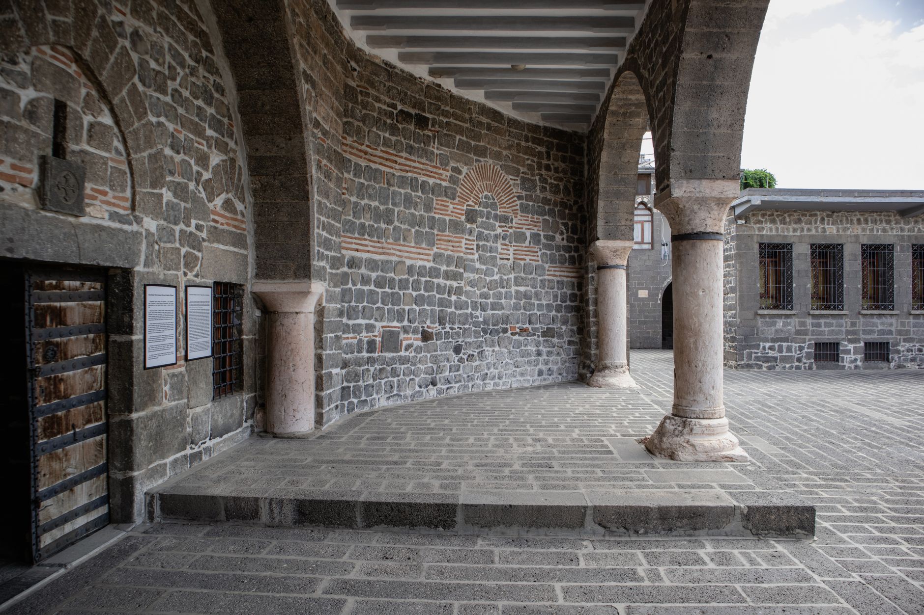 Interior view of a Diyarbakır courtyard with stone walls and arches.