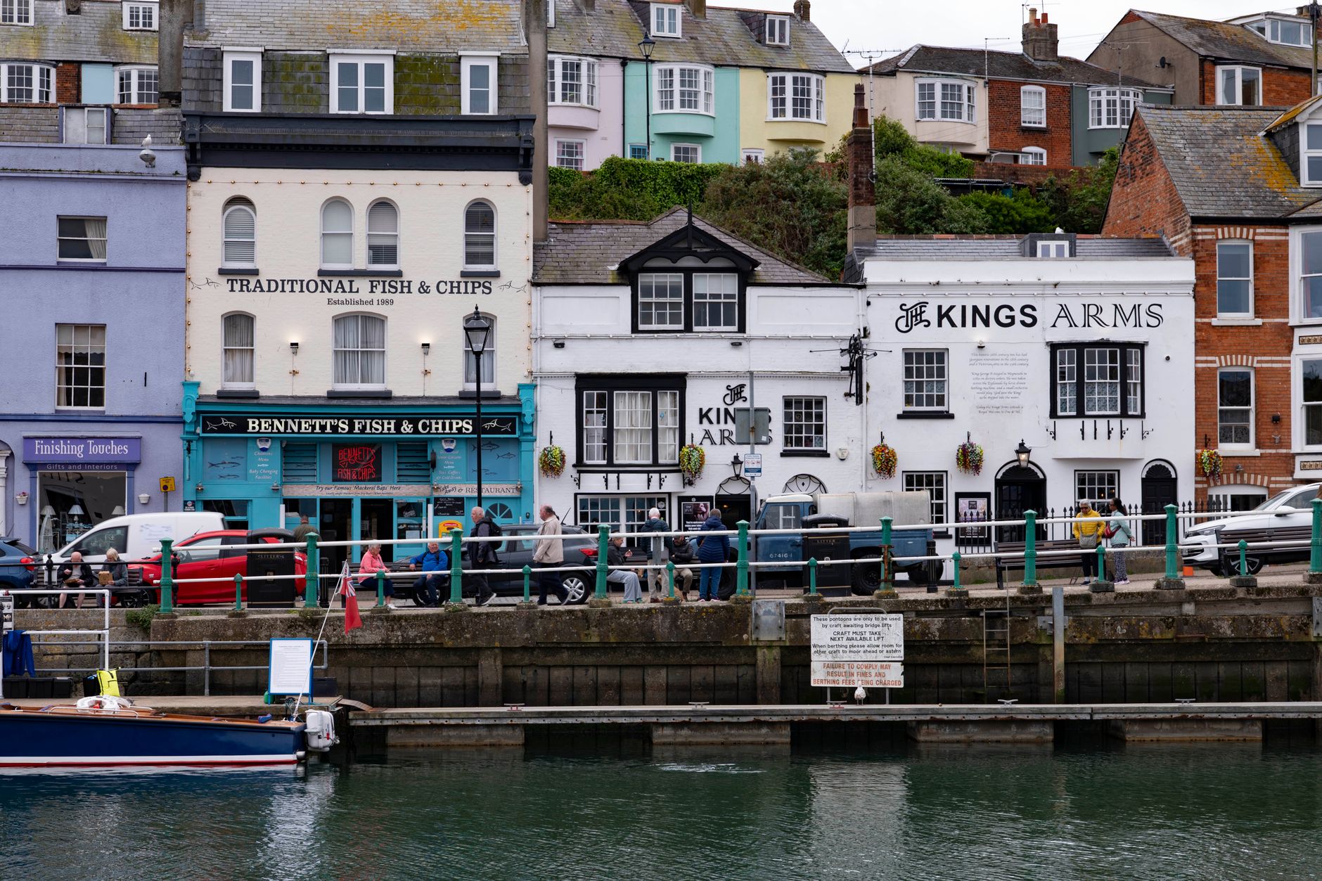 View of waterfront restaurants and fishing boats in a picturesque harbor setting.