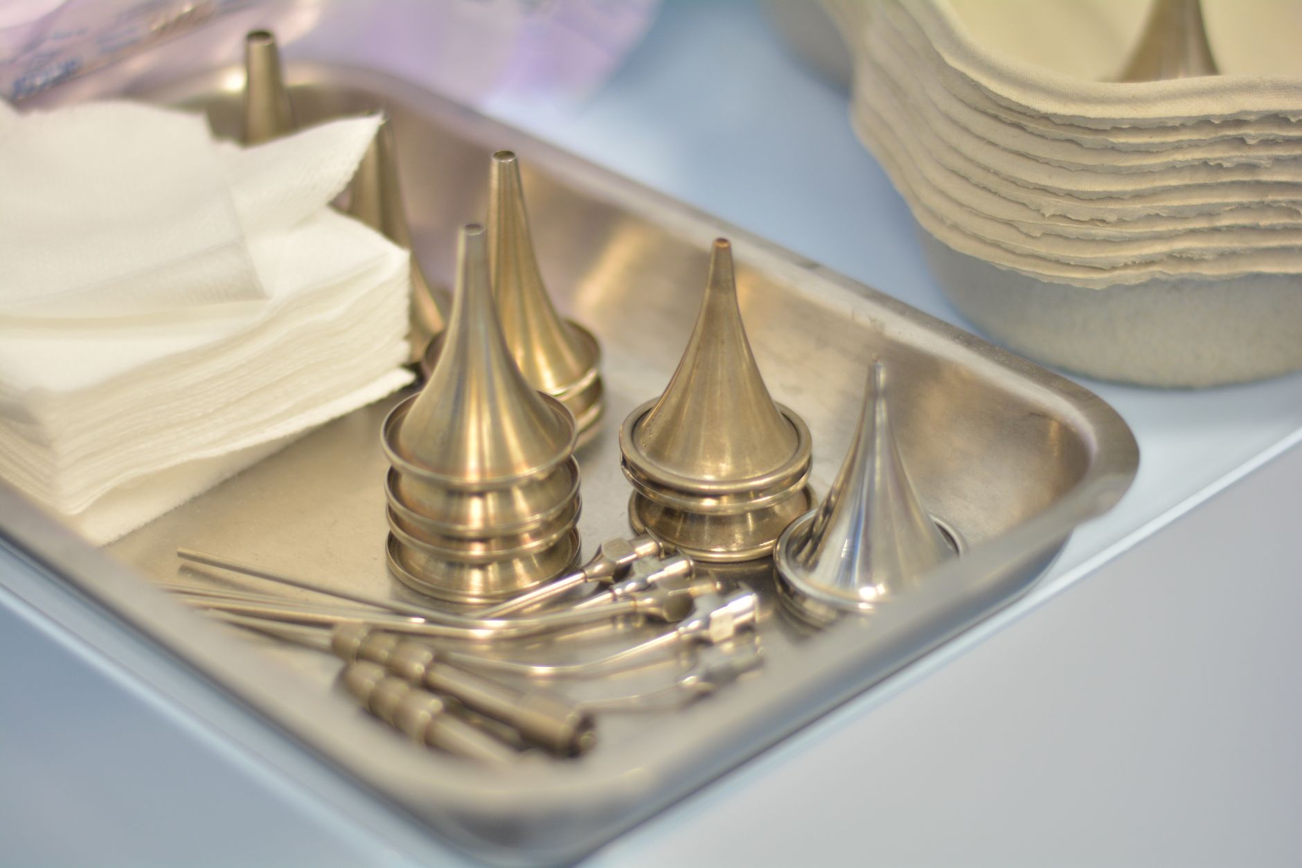 A tray with metallic surgical tools and paper towels for endoscopic ear surgery preparation.