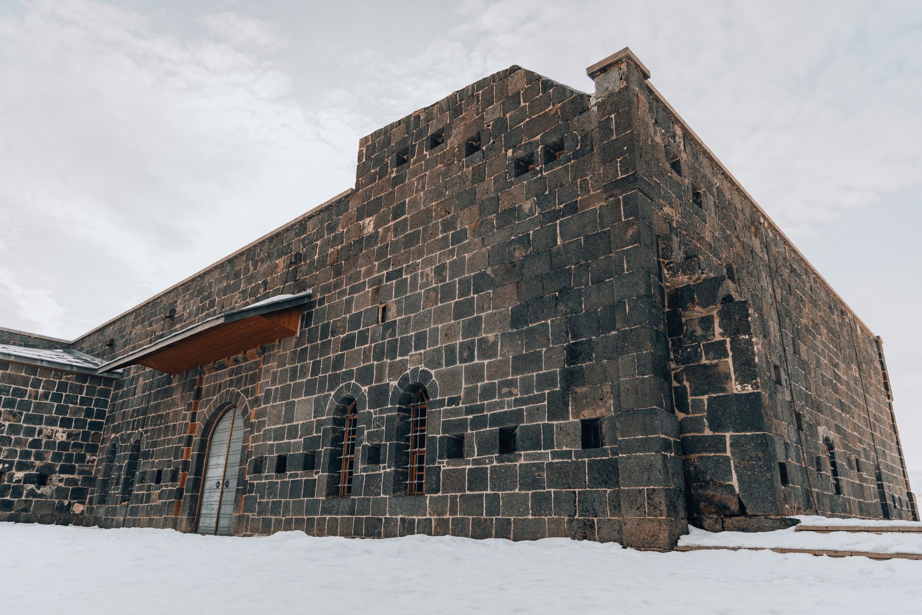 مبنى تاريخي مغطى بالثلوج في قارص، يُظهر هندسة معمارية حجرية فريدة تحت سماء شتوية.