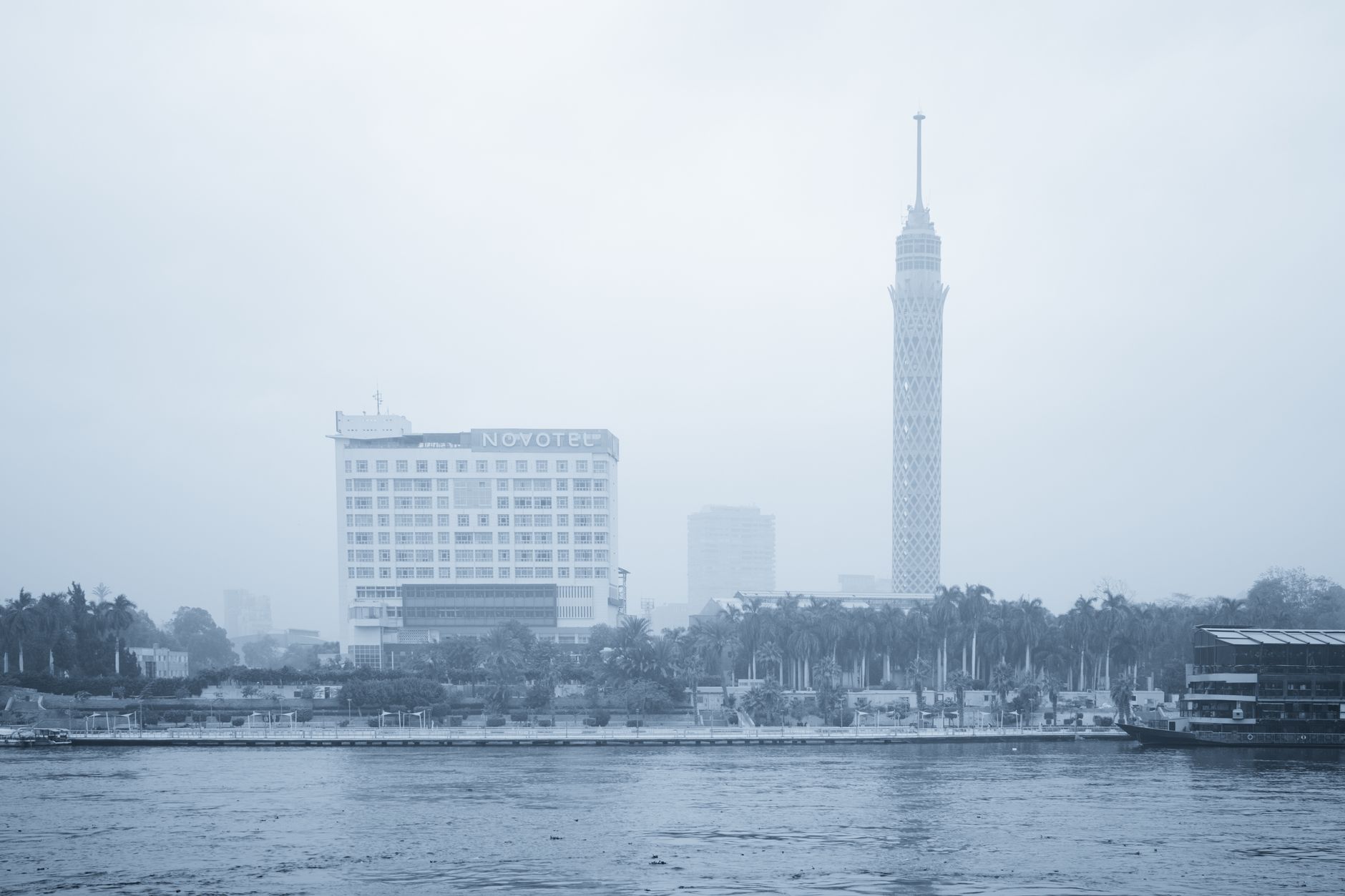 View of Cairo with Novotel hotel and Cairo Tower amidst a misty skyline.