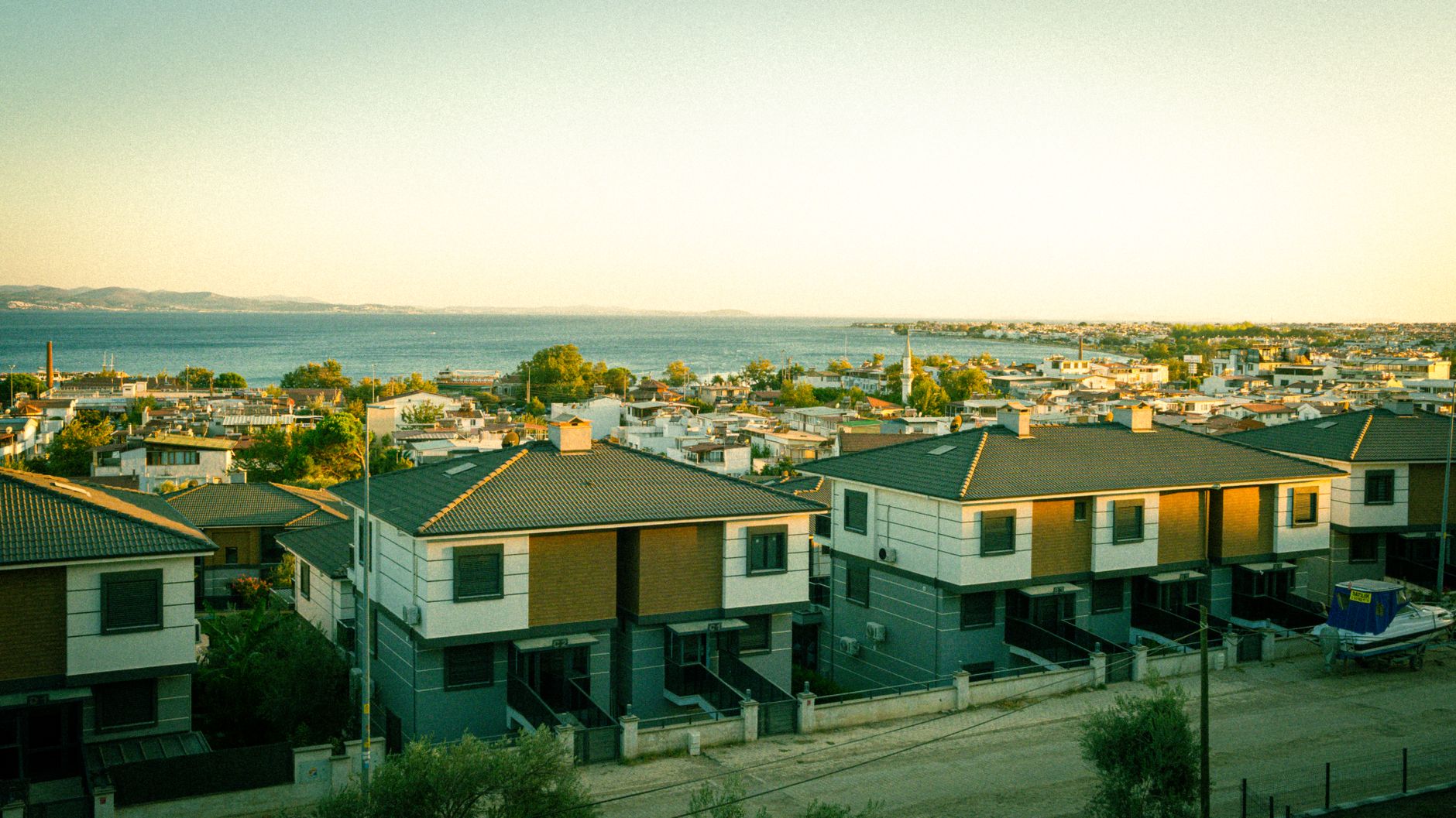Aerial view of modern homes by the sea during golden hour, showcasing coastal living.