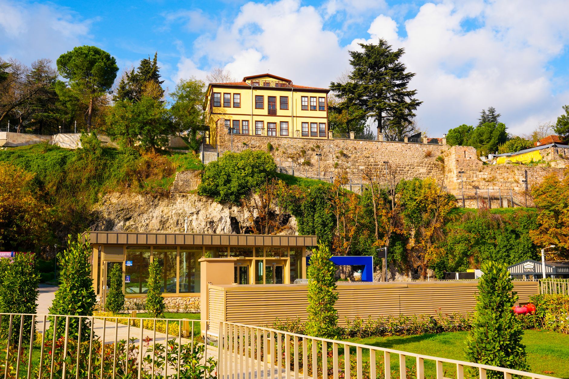 Serene park in Bursa with a historical building above, surrounded by greenery.