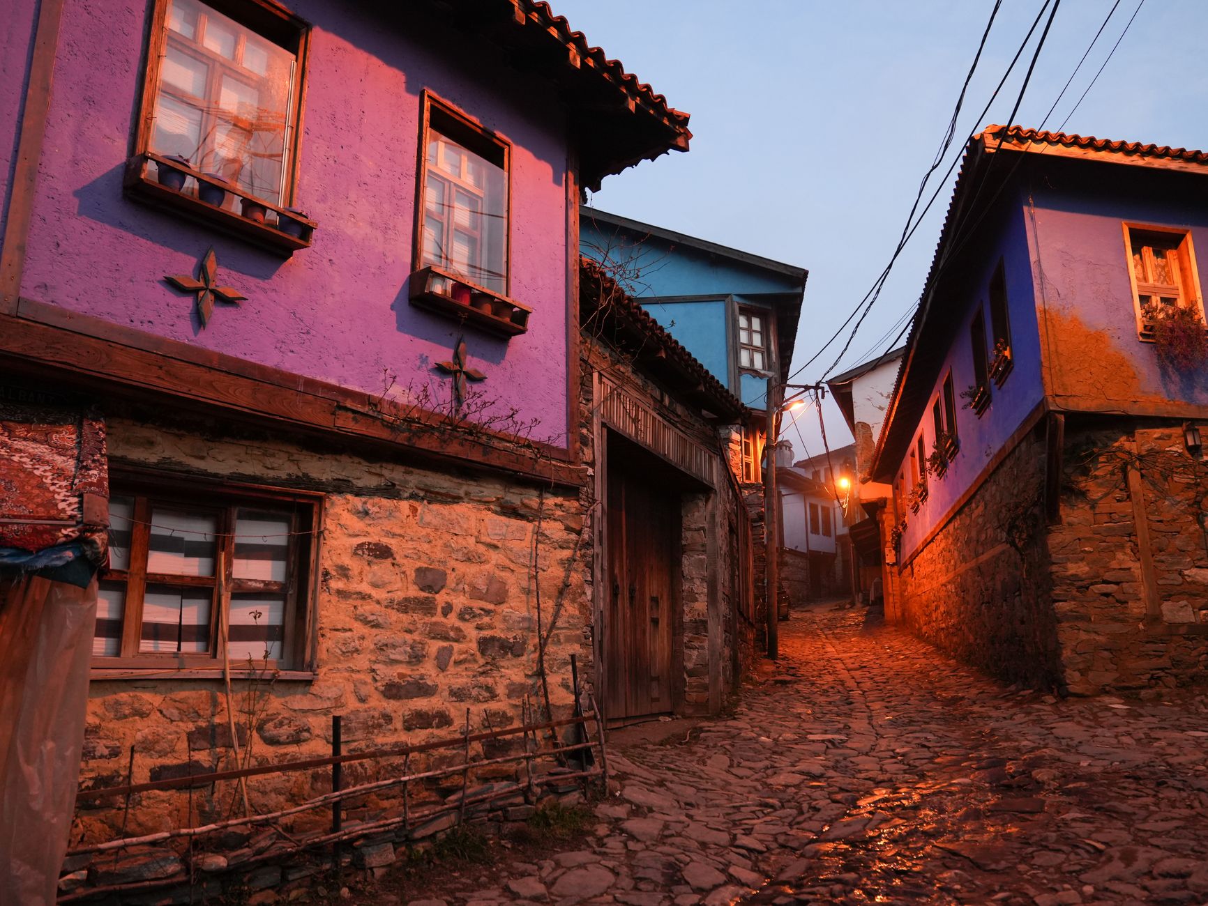 A quaint street in Cumalıkızık village with colorful Ottoman houses at dusk.