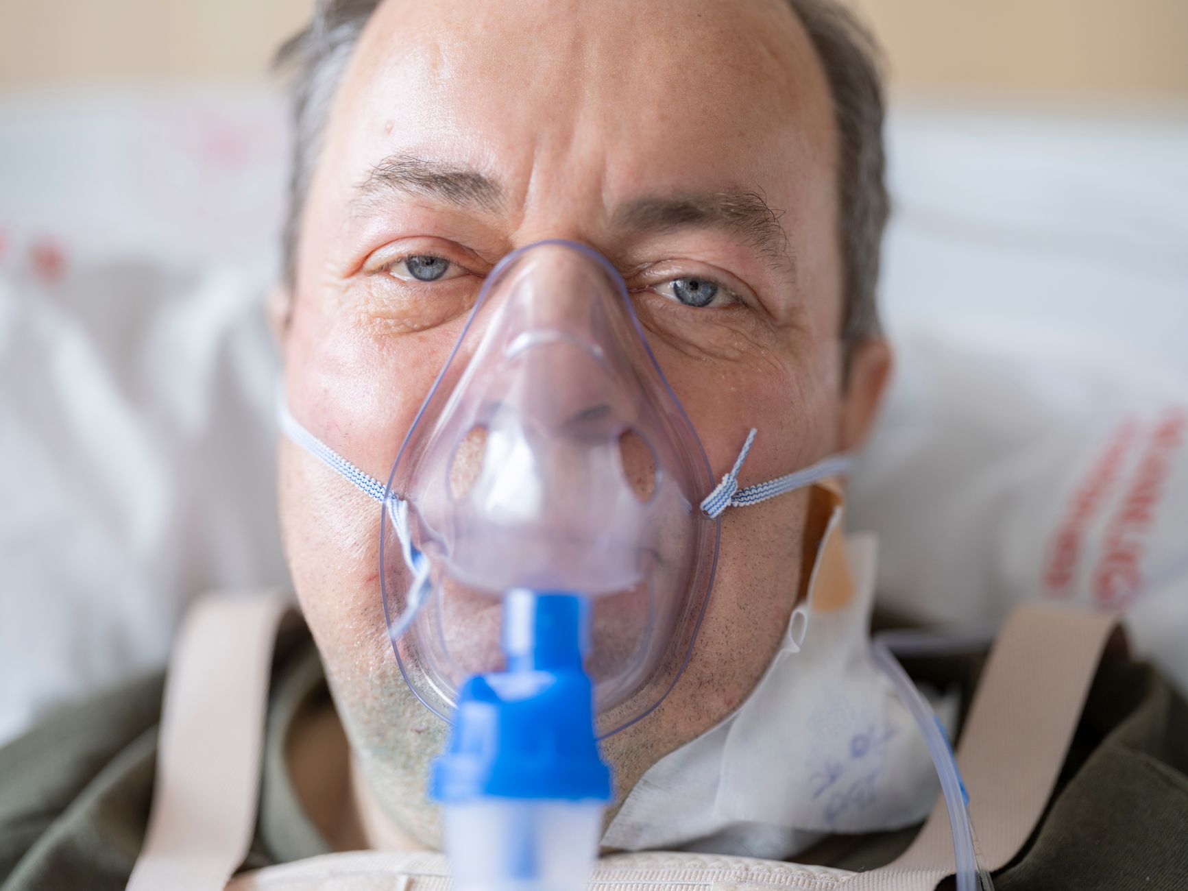 Smiling older patient in a hospital bed post-cataract surgery, showcasing satisfaction and clear vision.