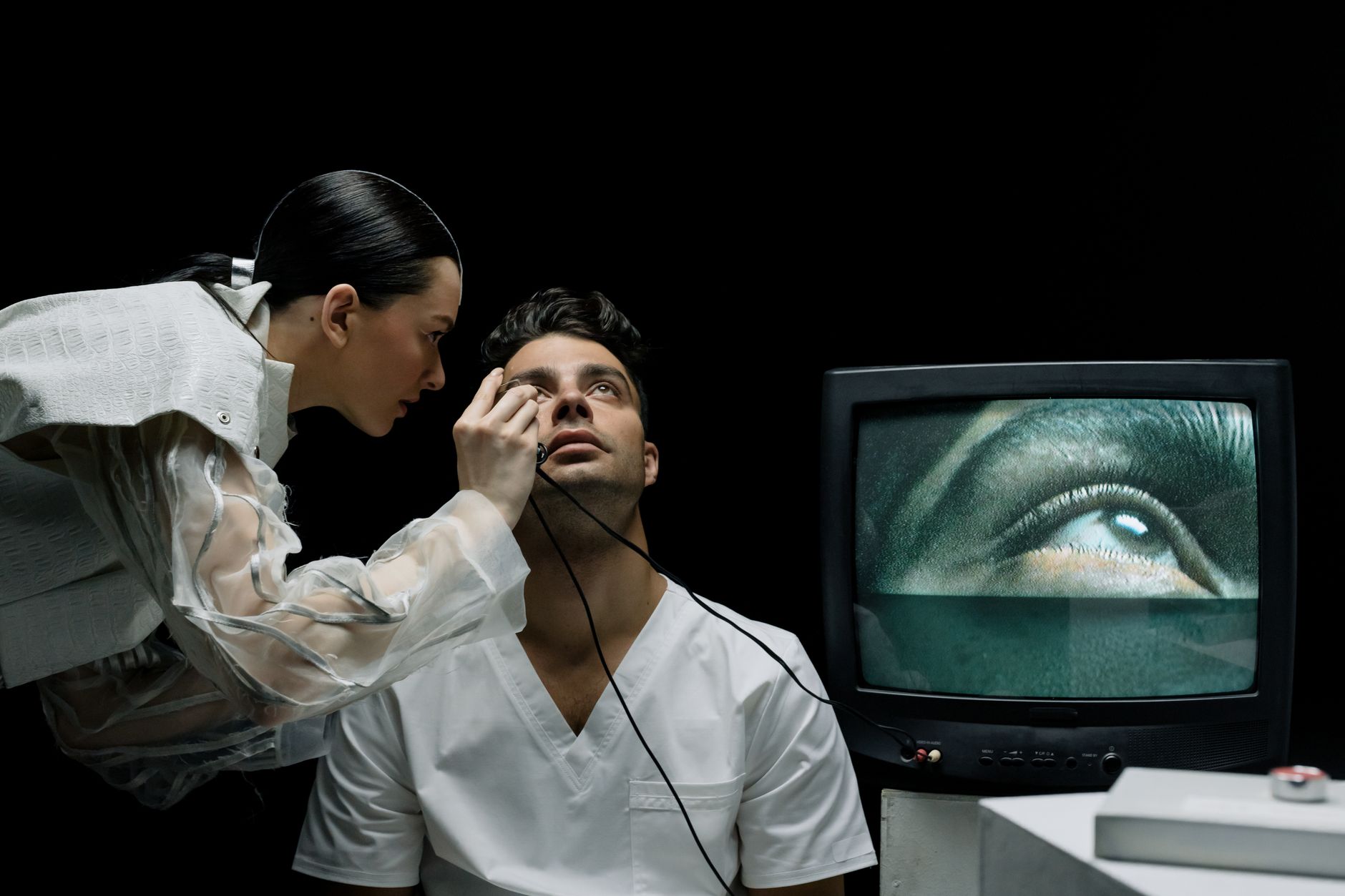 A patient being examined with a slit-lamp by a professional, with an eye displayed on a monitor.
