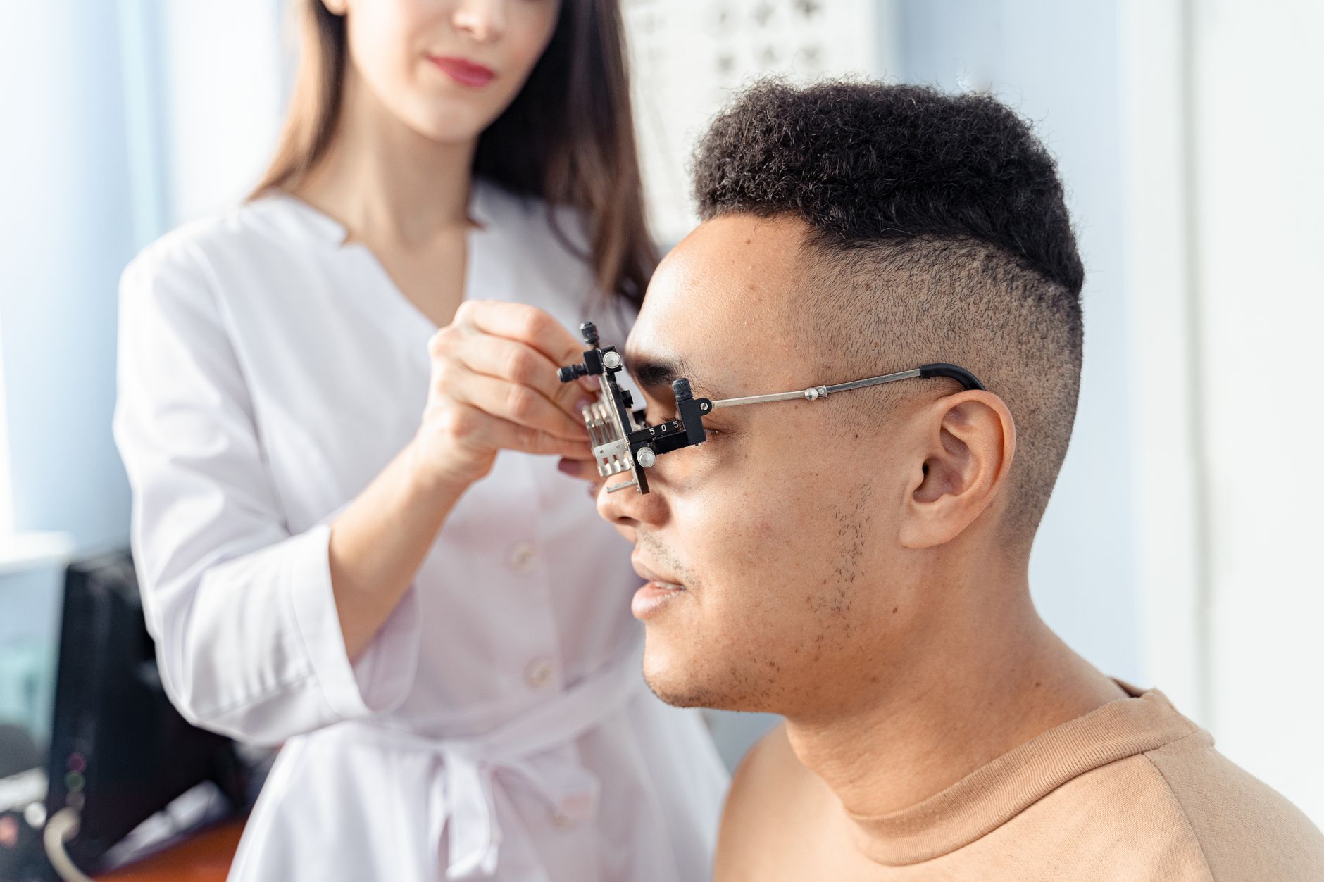 A doctor adjusts glasses on a patient's face during an eye exam.