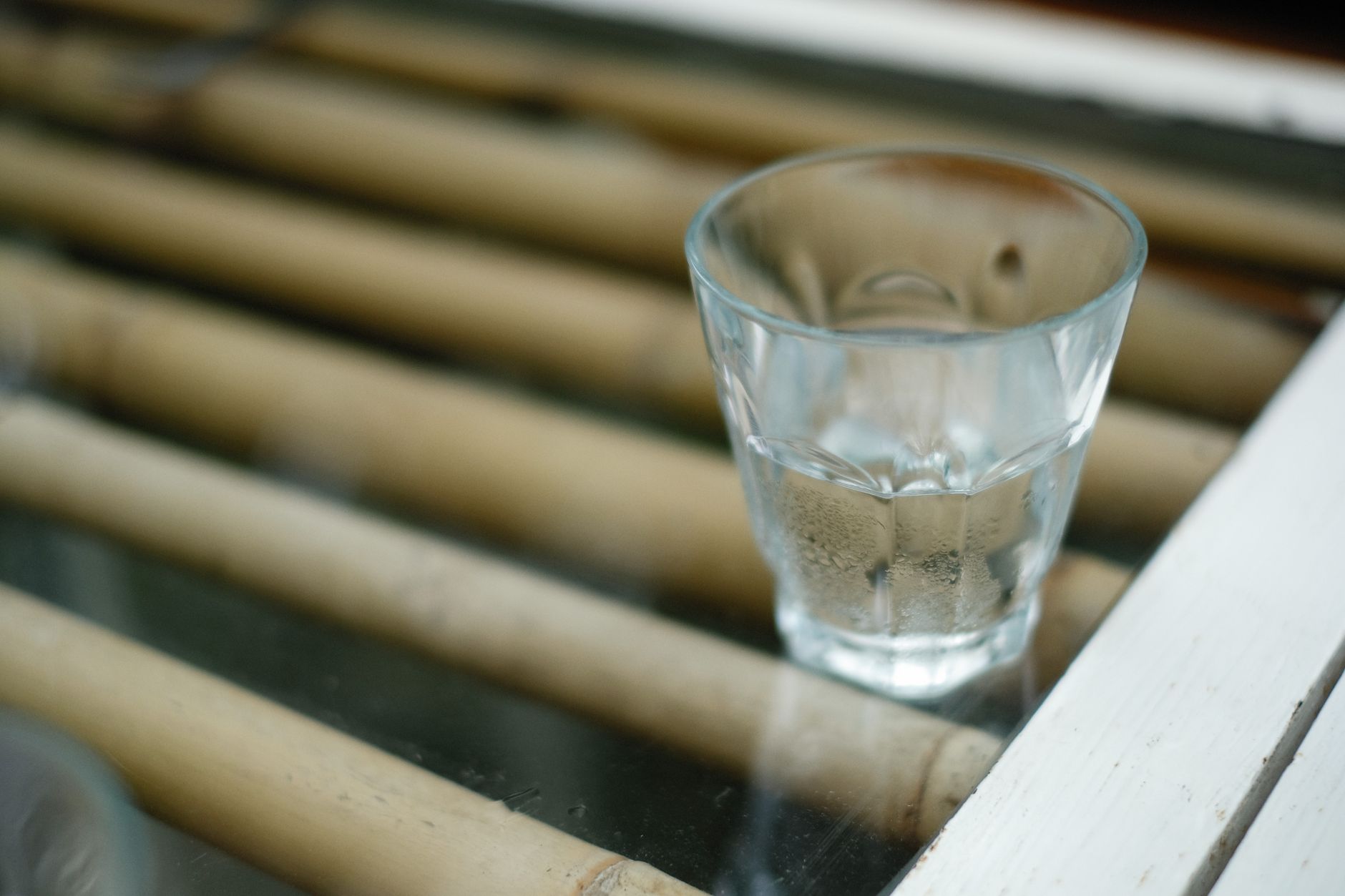 A close-up of a glass of water on a table with a bamboo surface.