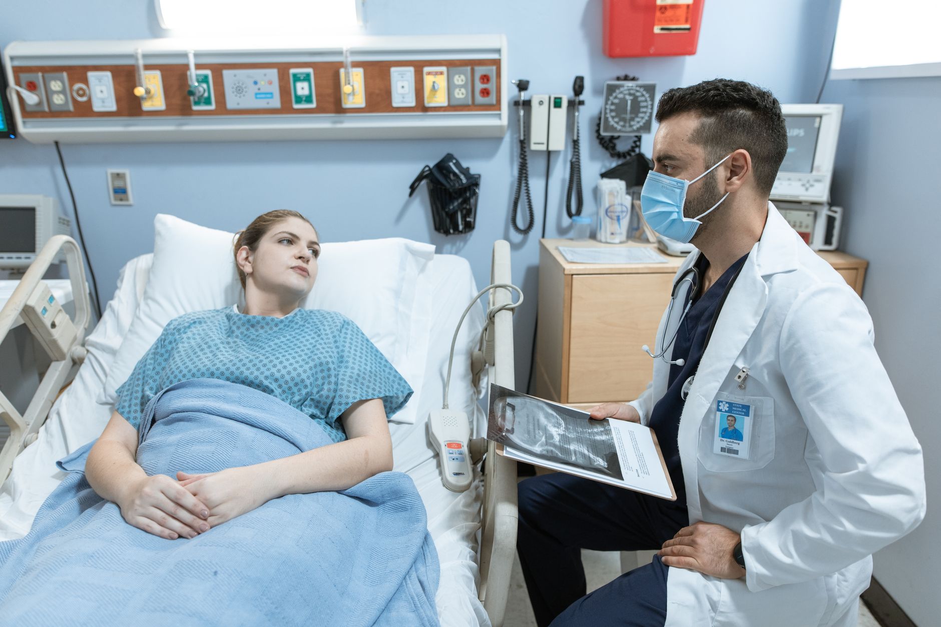 A nurse discusses pre-surgery fasting with a patient in a hospital room.