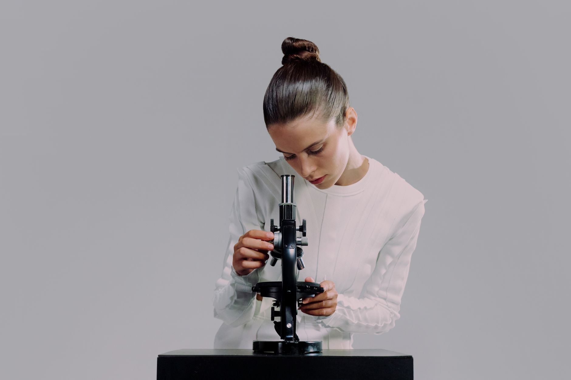 Woman examines scalp using a microscope, focusing on hair loss diagnostics.