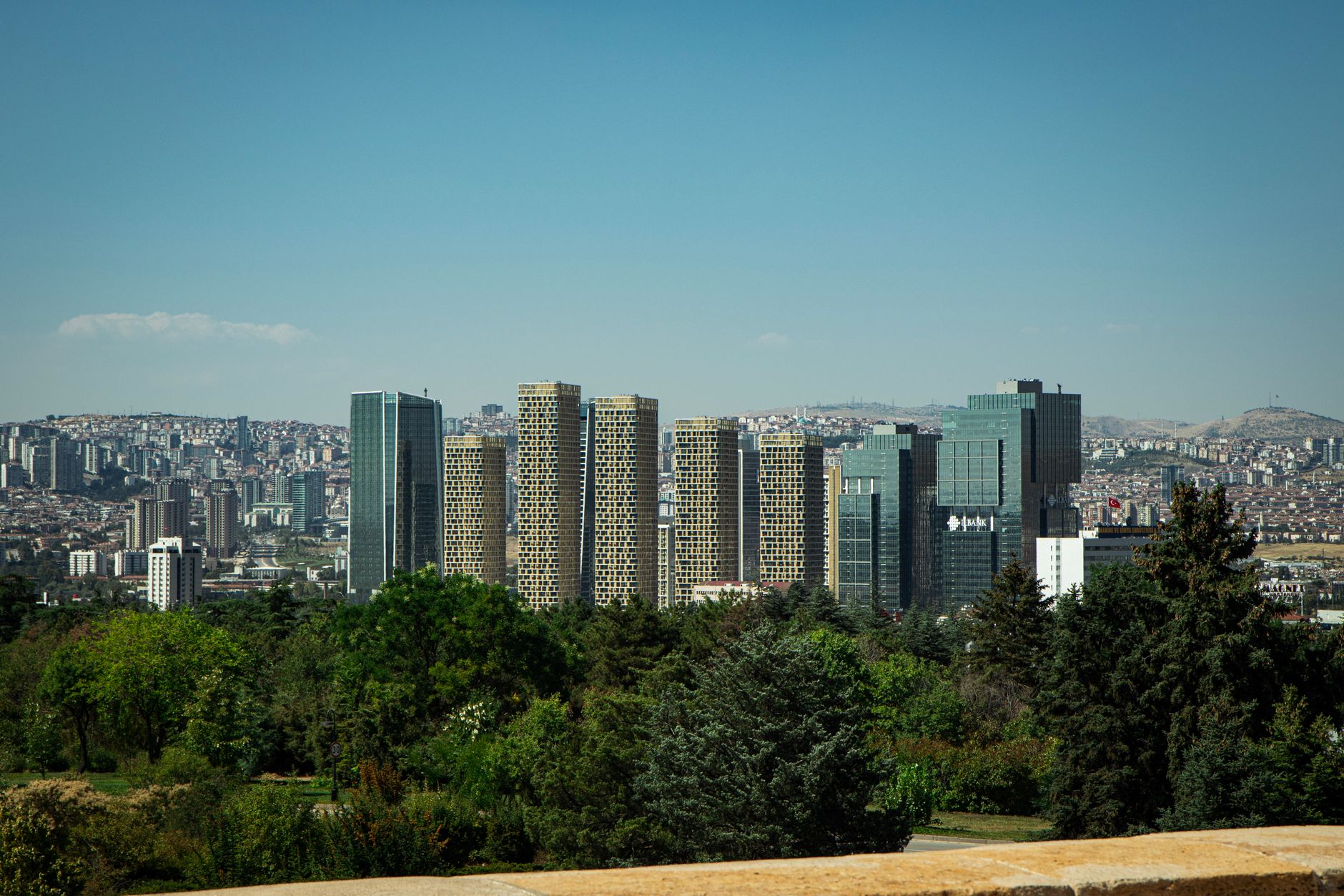 A view of Ankara featuring modern buildings, green foliage, and a serene skyline.