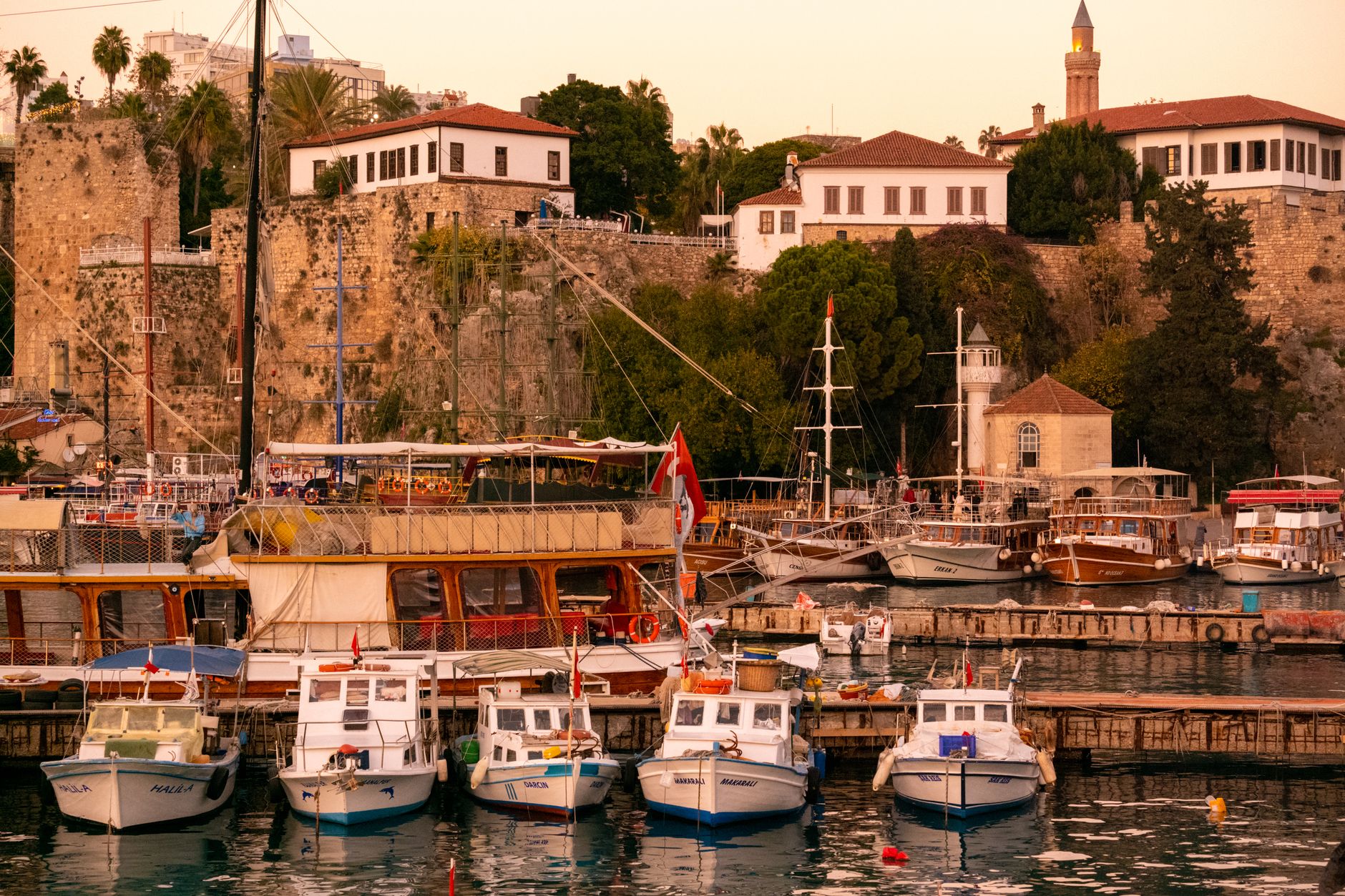 Beautiful sunset over Antalya's Old Town, showcasing fishing boats anchored in the harbor.