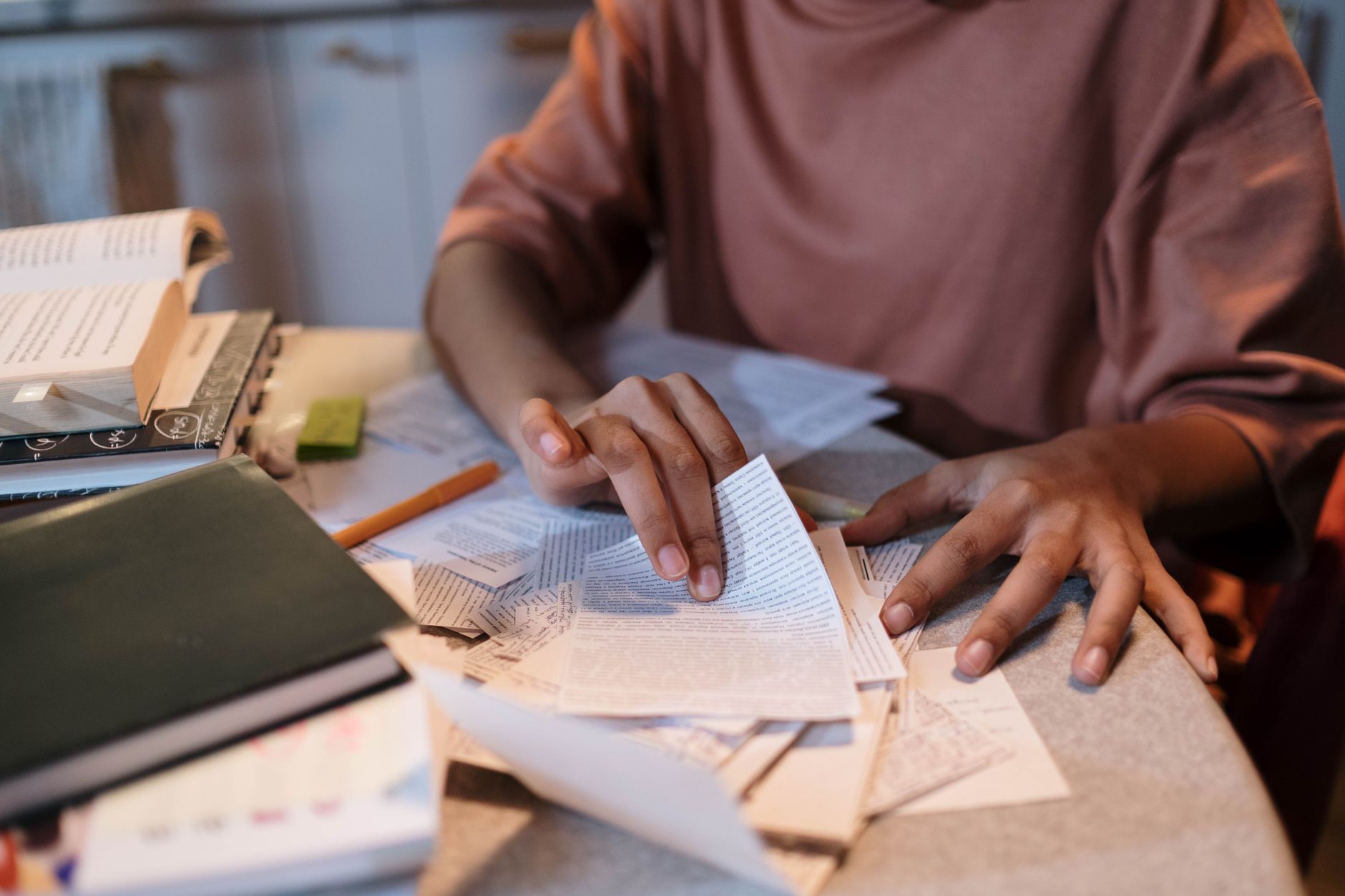 A student sorting through papers and forms on a desk, focused on medical leave documentation.