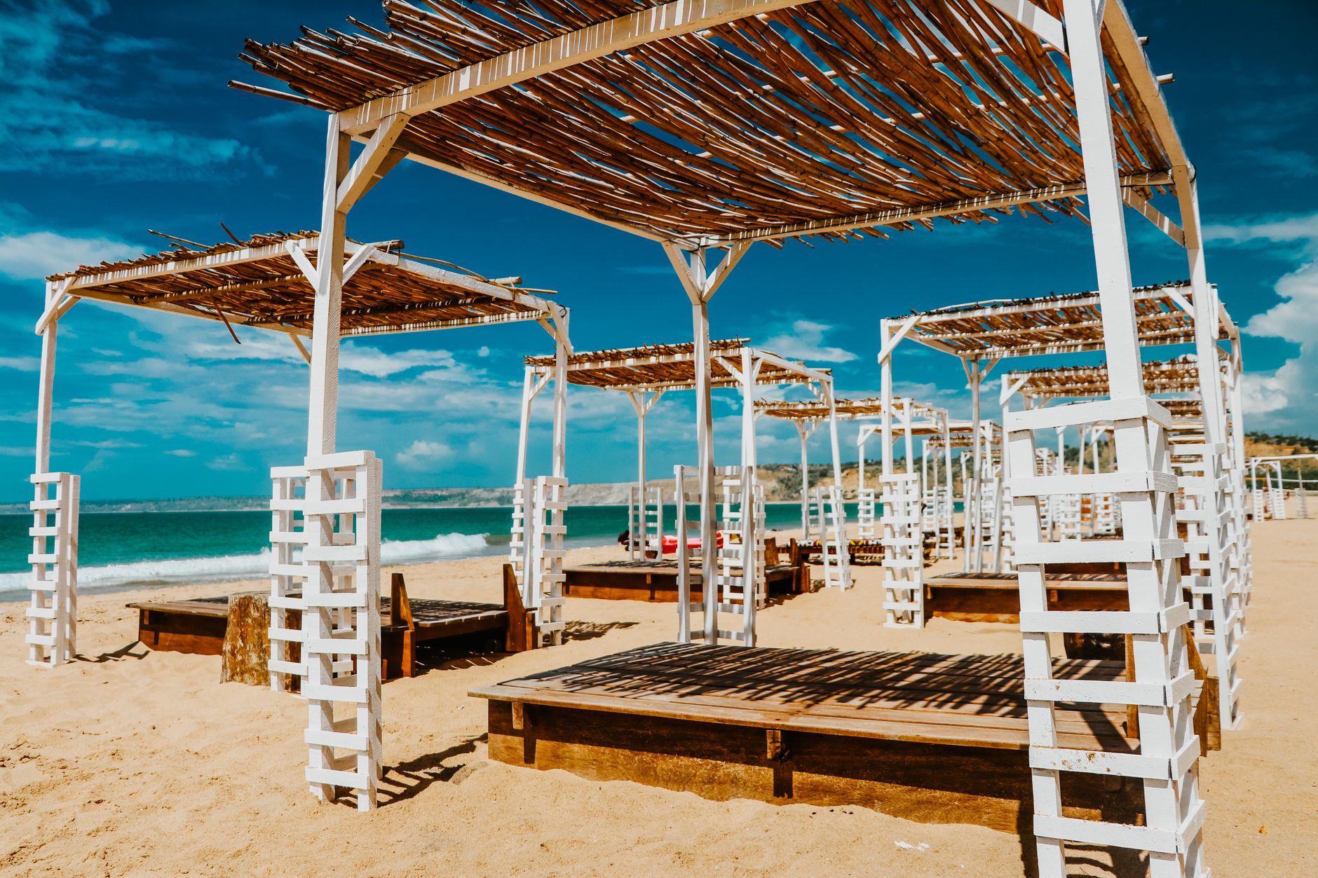 Sandy beach in Yenifoça featuring sunbeds and umbrellas under a clear blue sky.