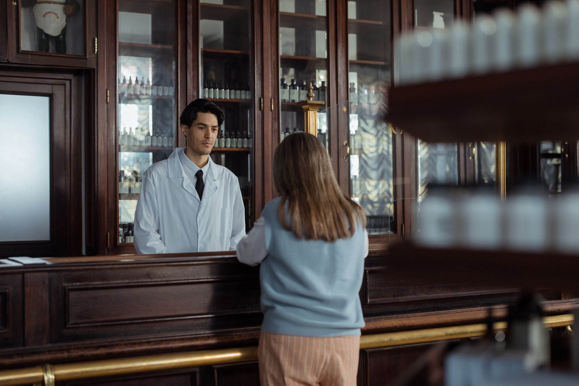 Pharmacist explaining medication plan to patient at a pharmacy counter.