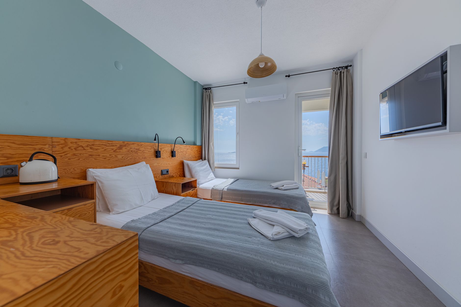 Bright recovery room featuring twin beds, modern decor, and a sea view balcony in Istanbul.