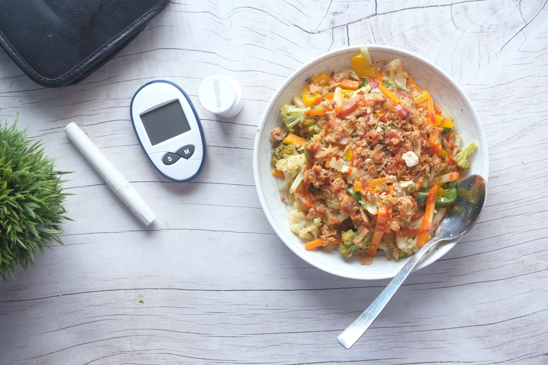 A nutritious bowl of mixed vegetables and lean protein, with a glucose meter nearby.