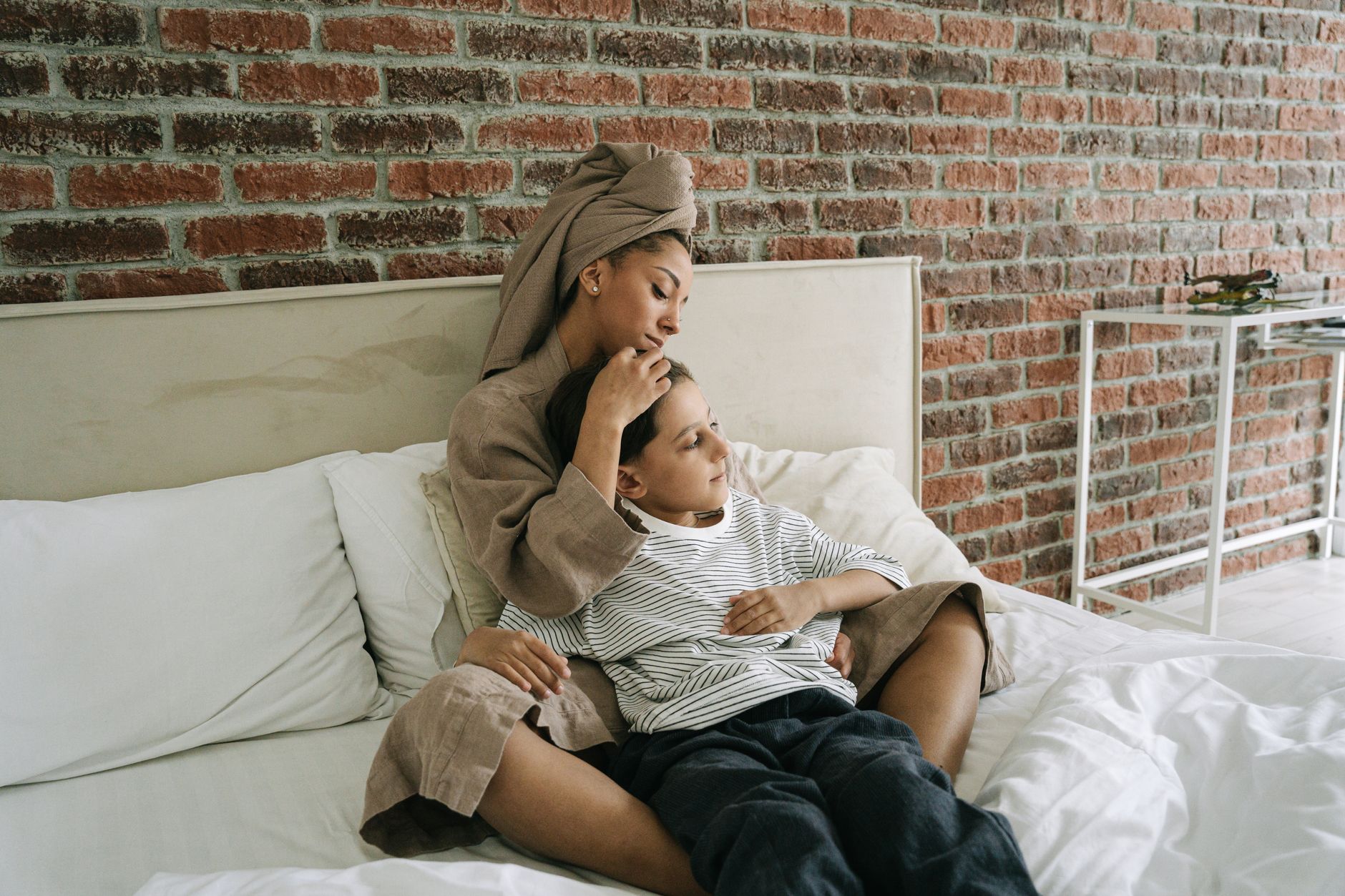 A mother seated beside her child on a sofa bed in a cozy room.