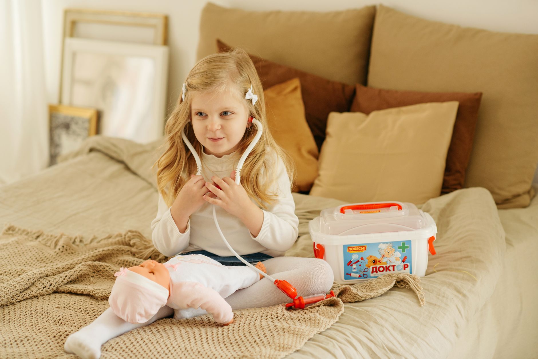 A young girl pretending to be a doctor with a toy medical kit and doll.