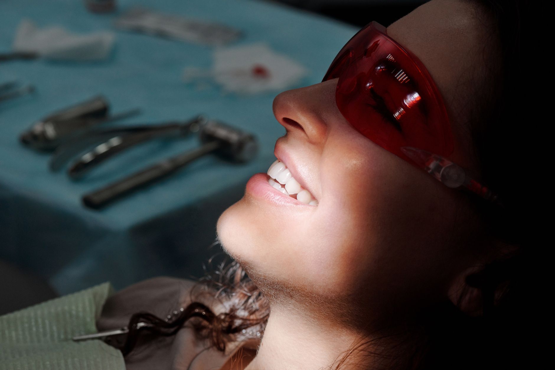 Patient receiving laser dental treatment with protective glasses in a clinic.