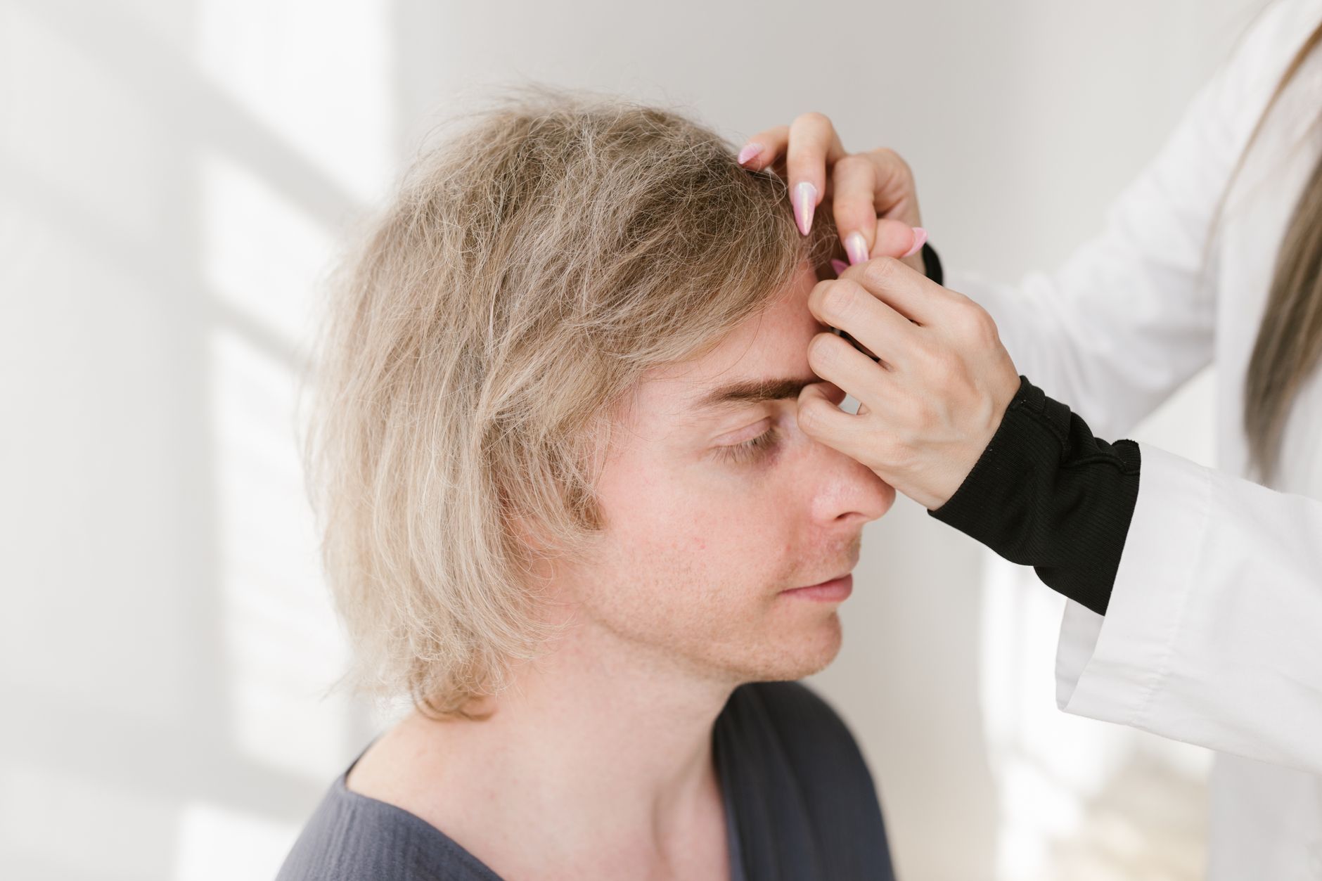 Male patient undergoing hairline restoration treatment with a specialist.