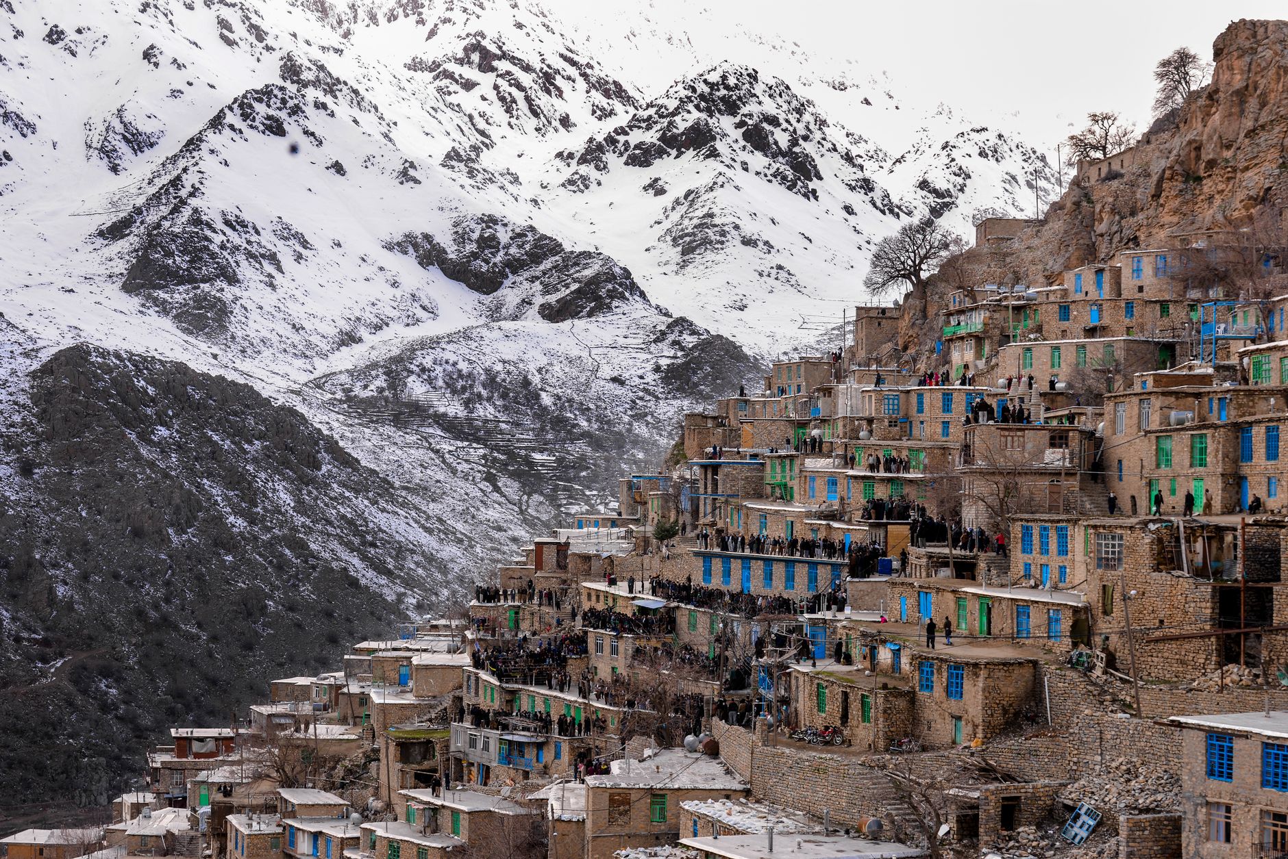 منظر خلاب لقرية كردية تقليدية في هكاري، تضم بيوتًا حجرية محاطة بجبال مغطاة بالثلوج.