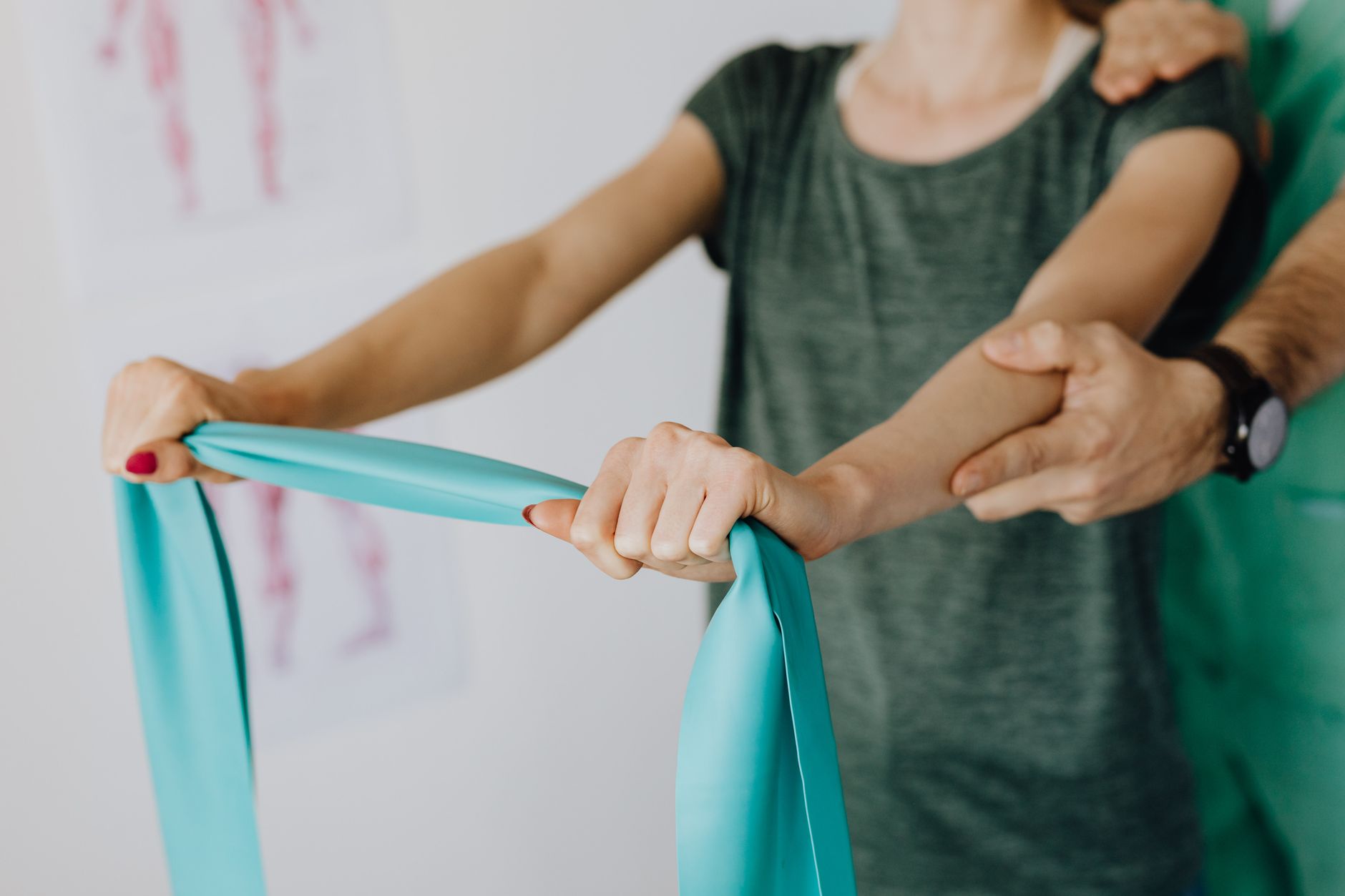 A patient performs hand therapy with a specialist using a resistance band in a clinic.