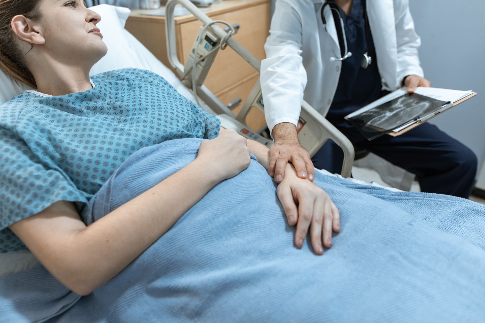 A doctor gently examines a patient's hand in a hospital setting, providing personalized care.