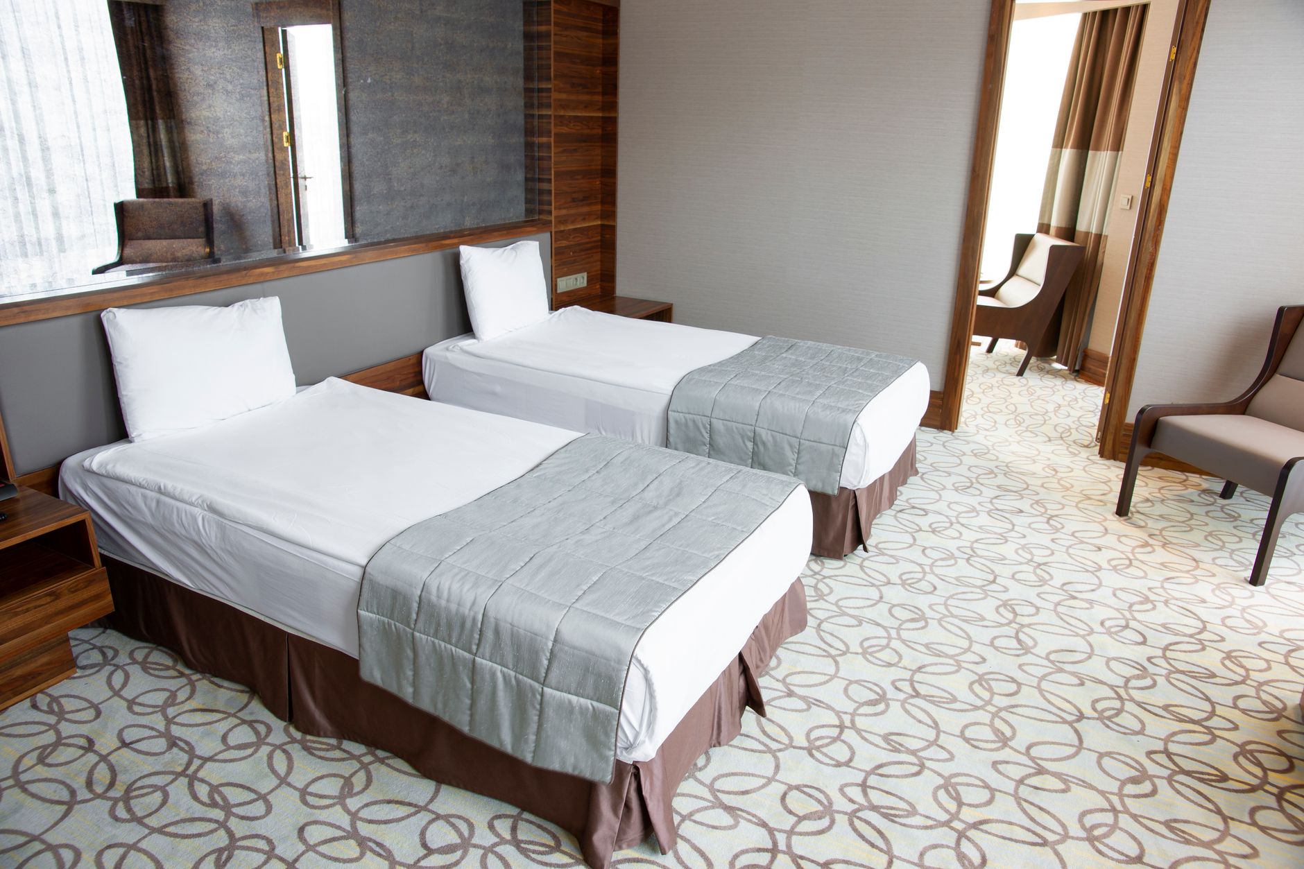 Spacious hotel-like patient room with two beds, modern decor, and soft lighting.