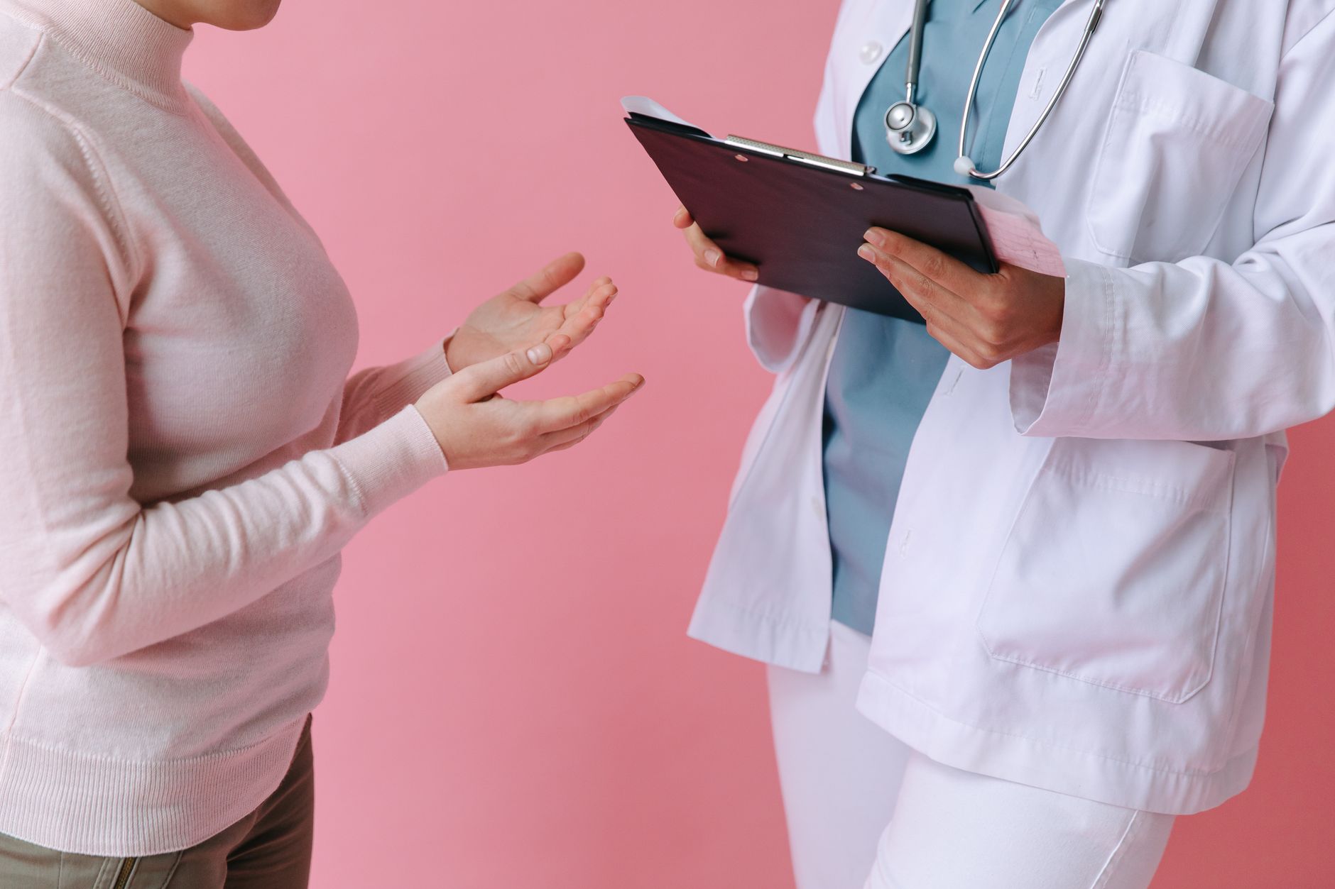 A plastic surgeon consulting with a patient in a pink-themed clinic.