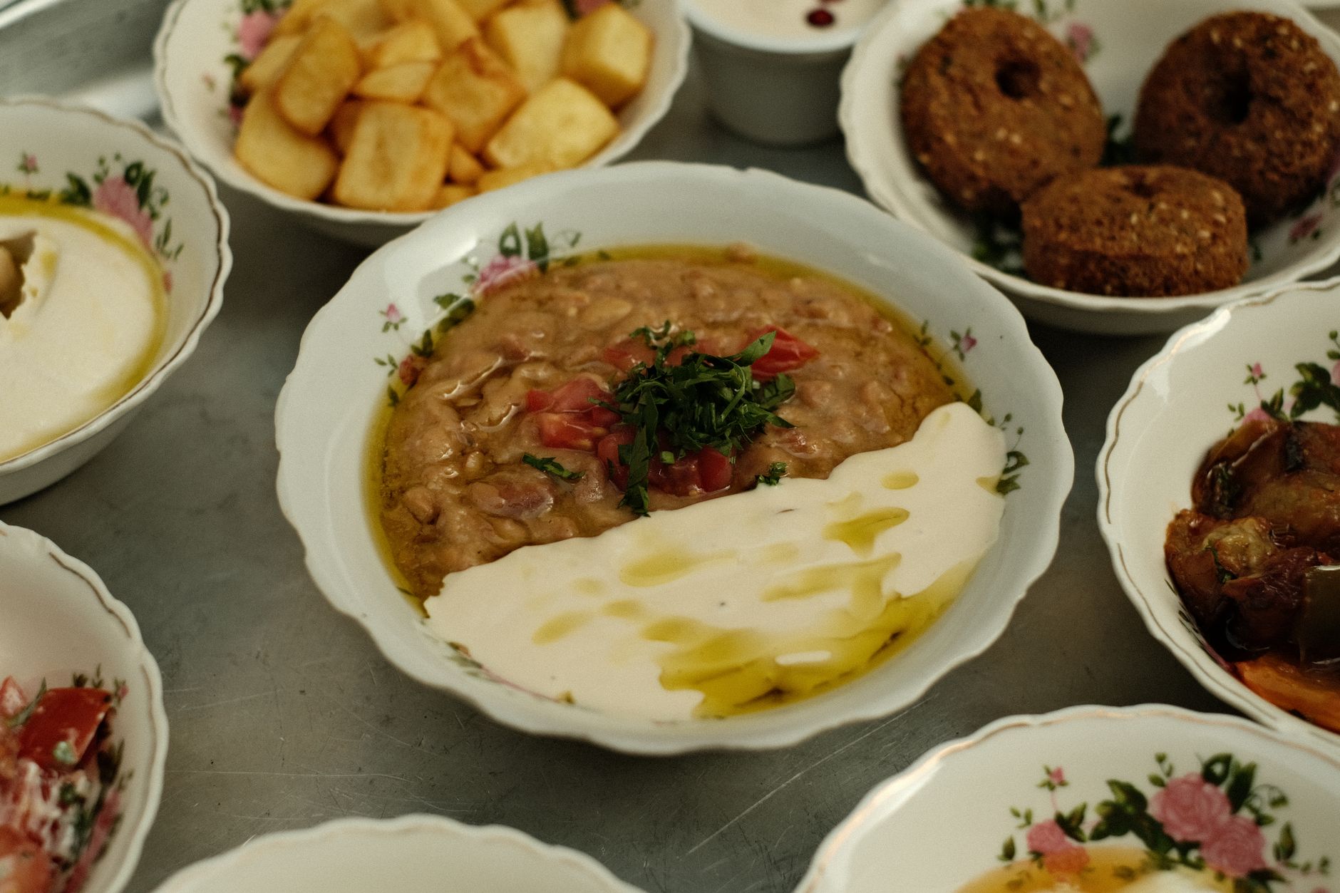A variety of Turkish hospital meals, including lentil dip, yogurt, and fried potatoes, displayed in ornate bowls.