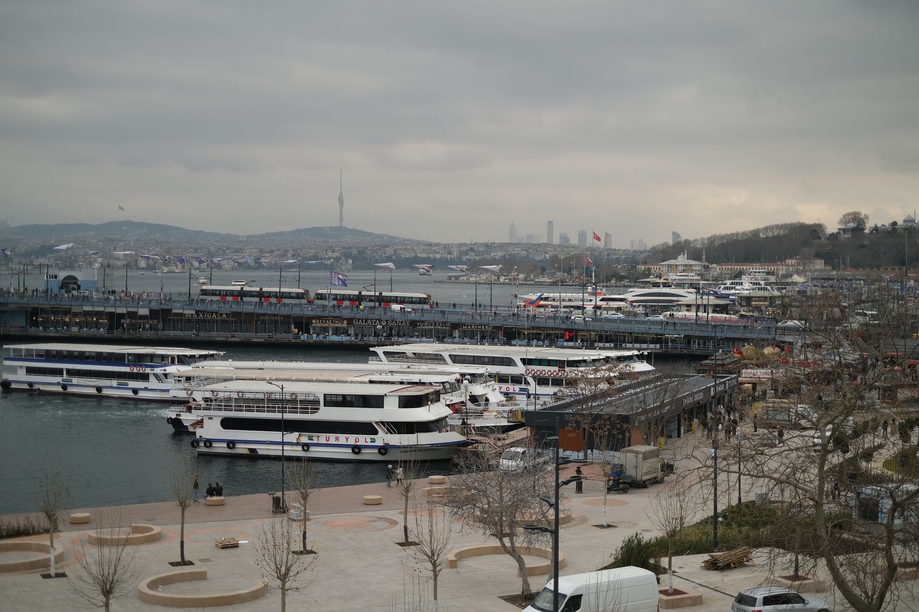 A scenic view of Istanbul's waterfront featuring boats, a cloudy sky, and the city skyline in the background.