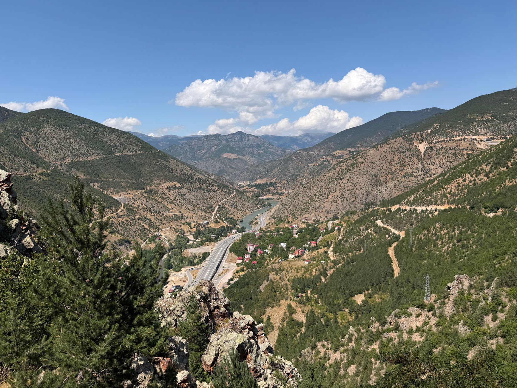 森林覆盖的屈雷山脉山谷全景，蜿蜒的河流和公路。