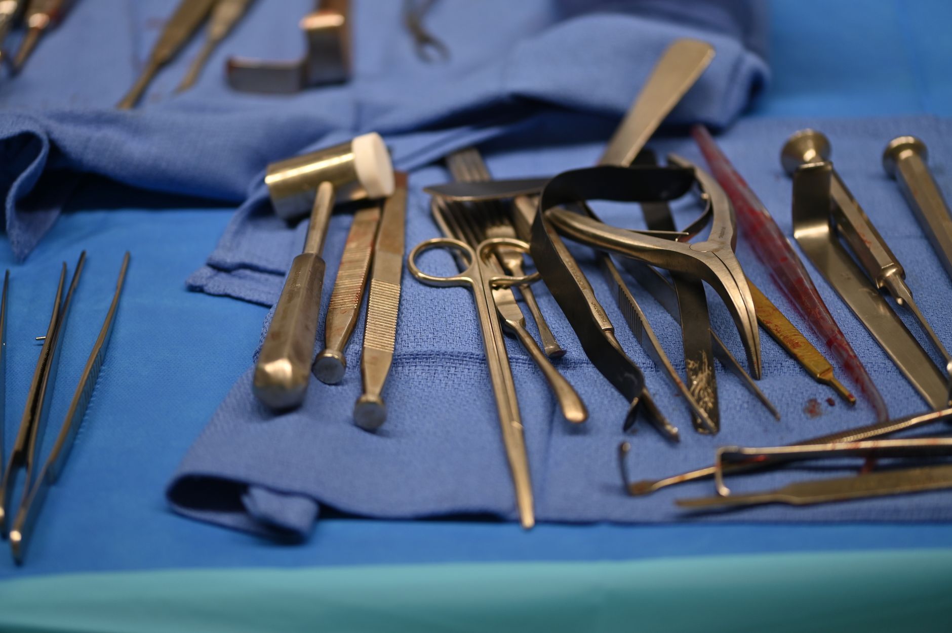 A collection of surgical instruments arranged on blue surgical drapes for a procedure.