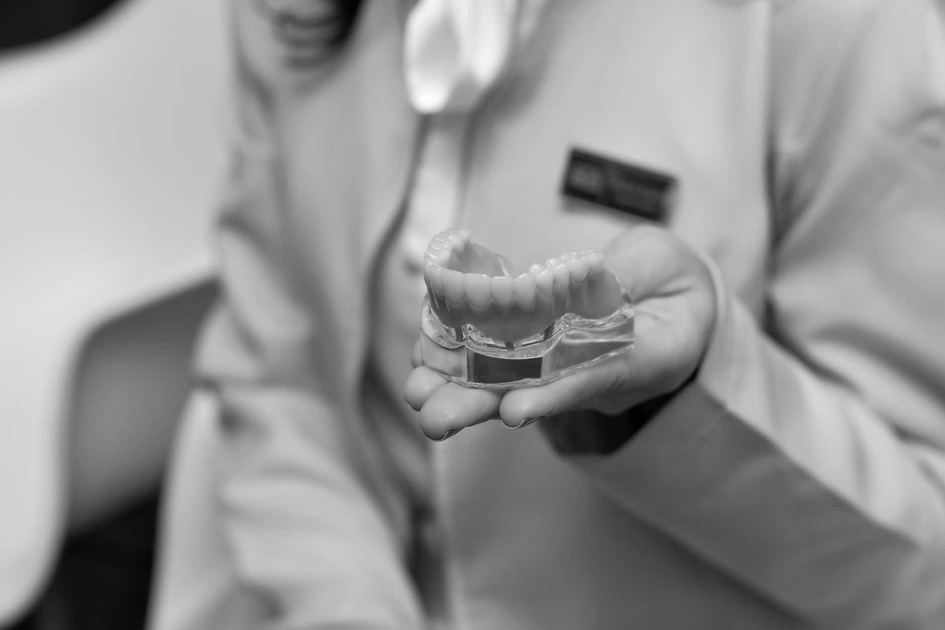 A dental professional holds a model of teeth during a consultation.