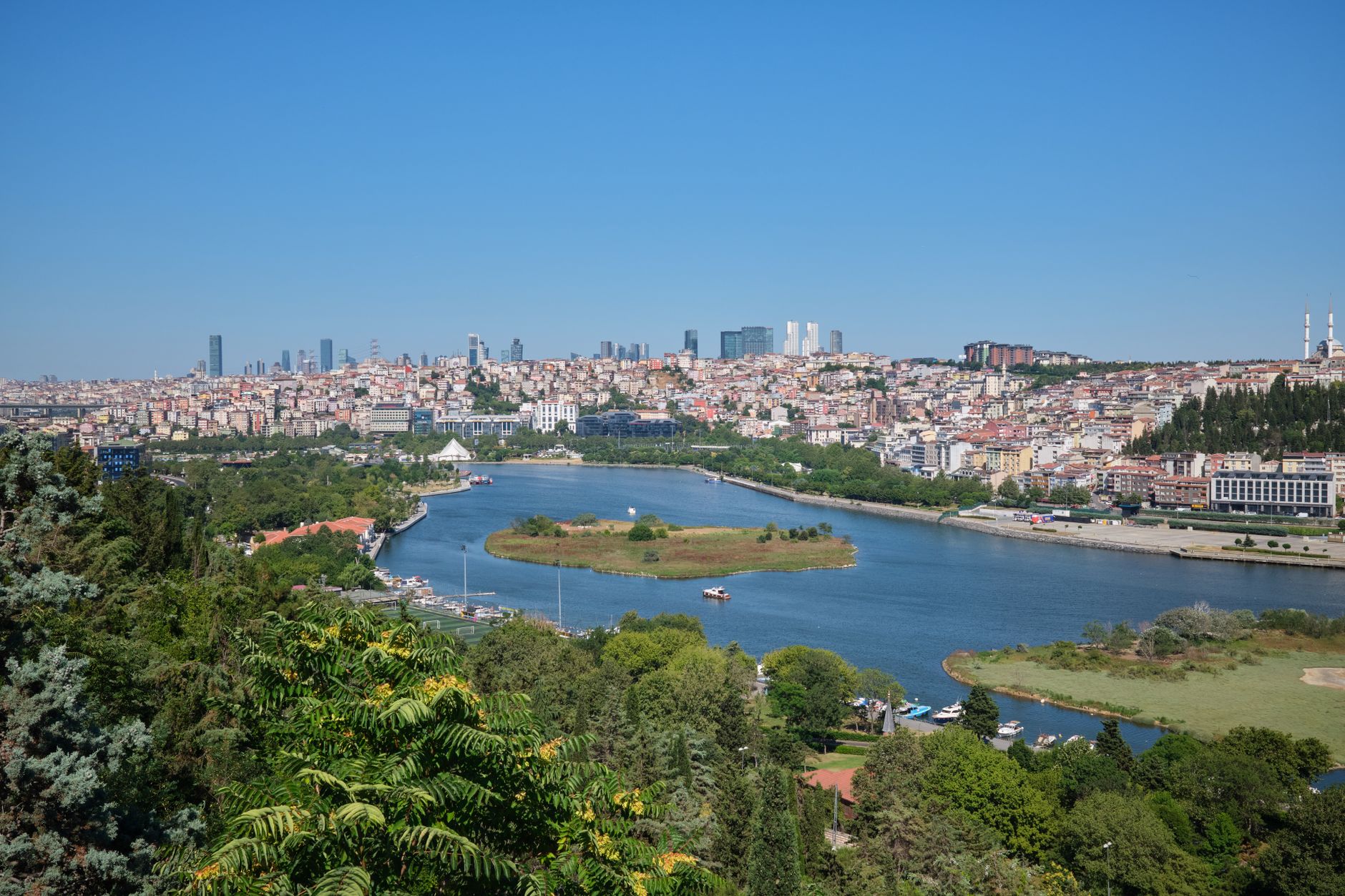 View of Istanbul skyline with a river and lush greenery, highlighting modern architecture.