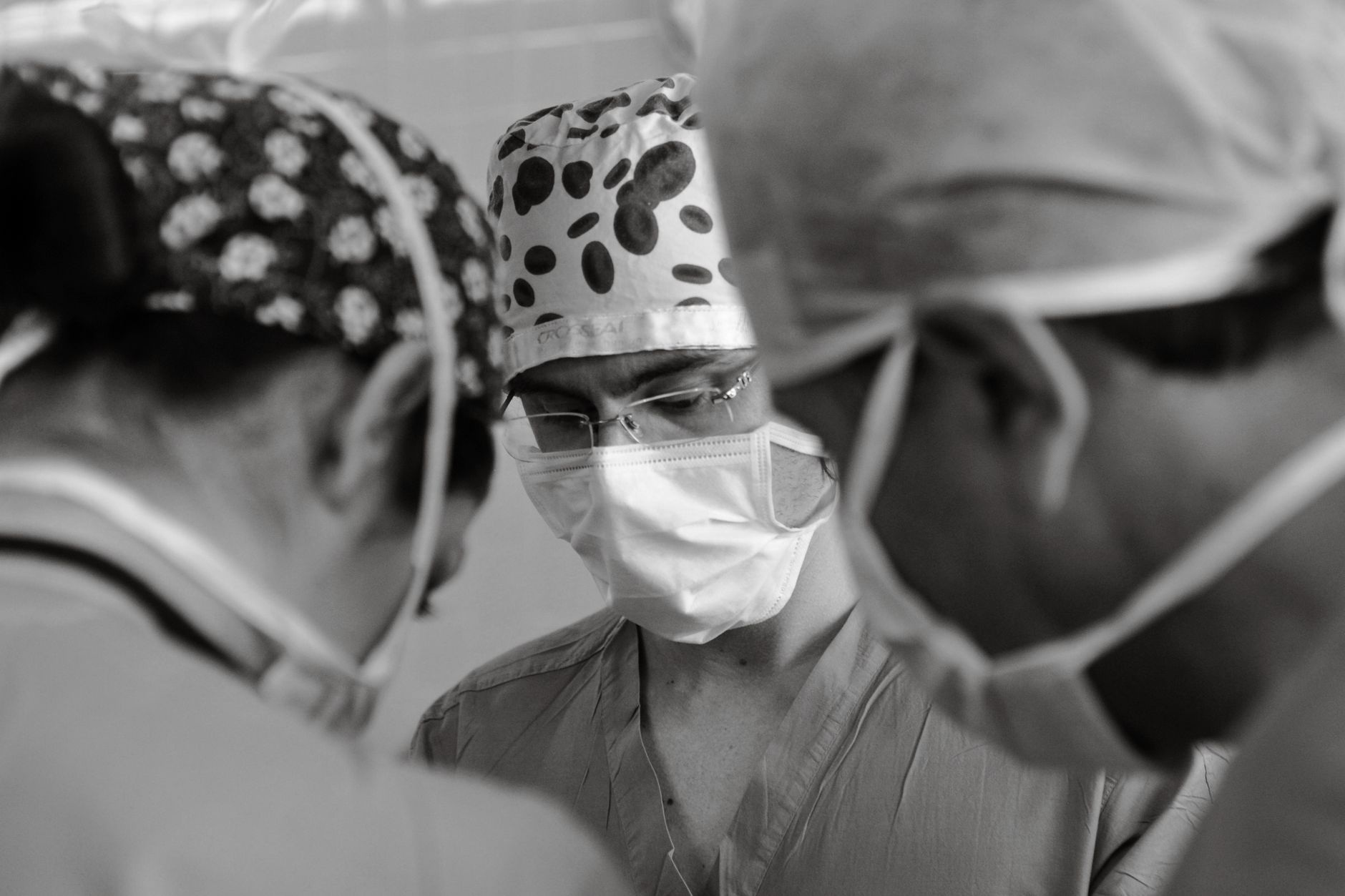Three surgeons in scrubs and masks focus intently during an operation.
