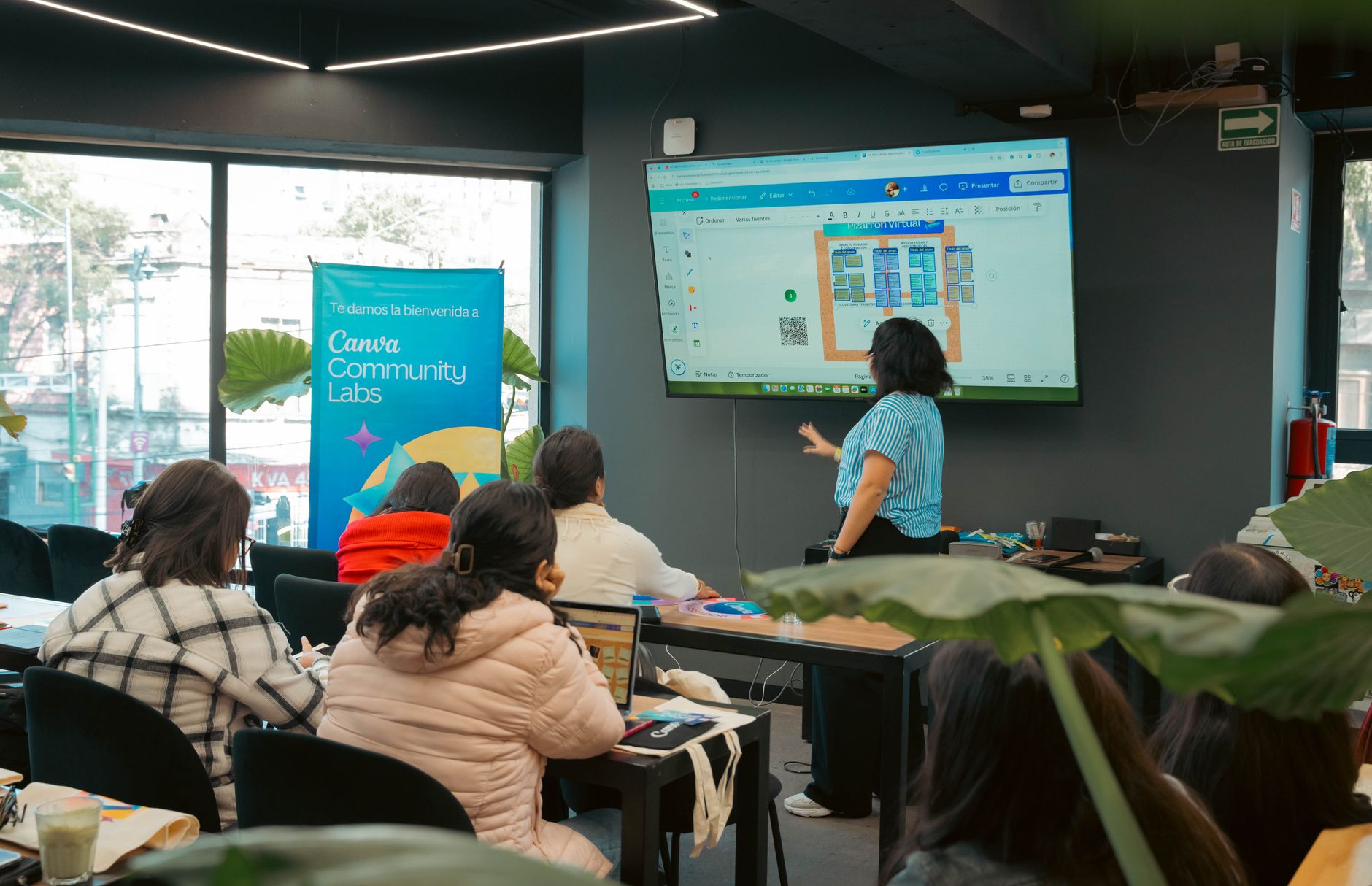Participants attending a Canva workshop with a presenter and a digital display.